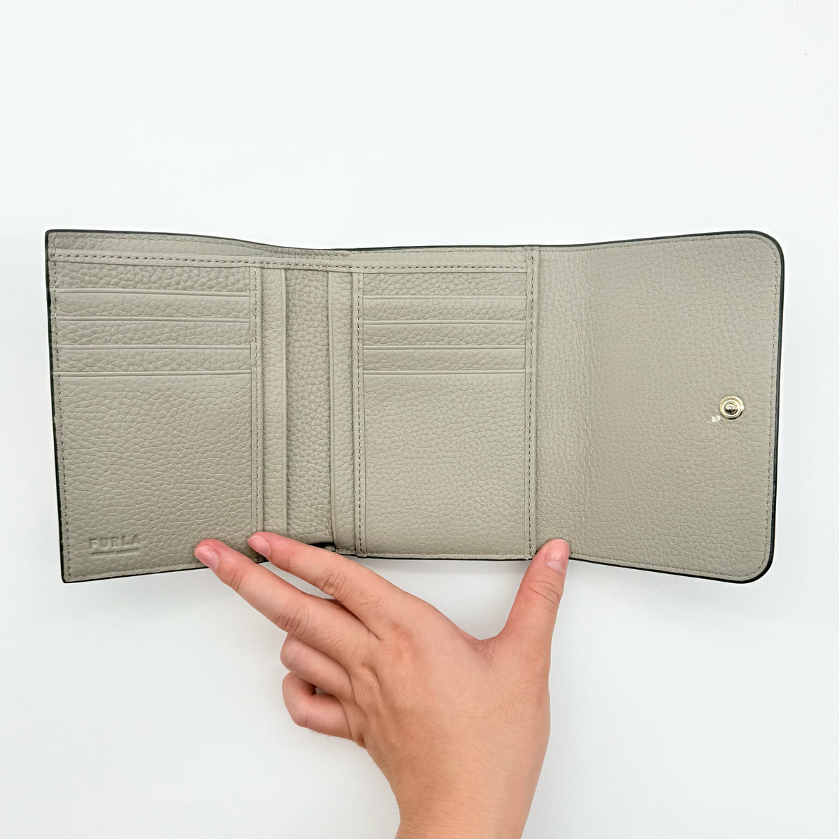 Furla Dafne Trifold Wallet in grey pebbled leather with gold-tone hardware and trifold interior, shown with original dust bag.