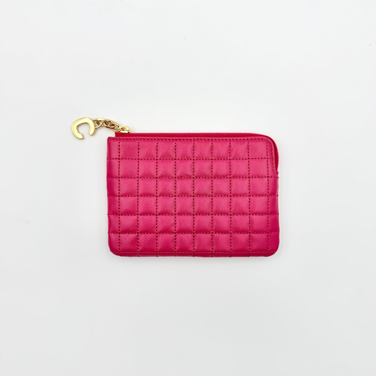Celine quilted pink coin and card wallet with gold C charm, displayed on a black Celine dust bag.