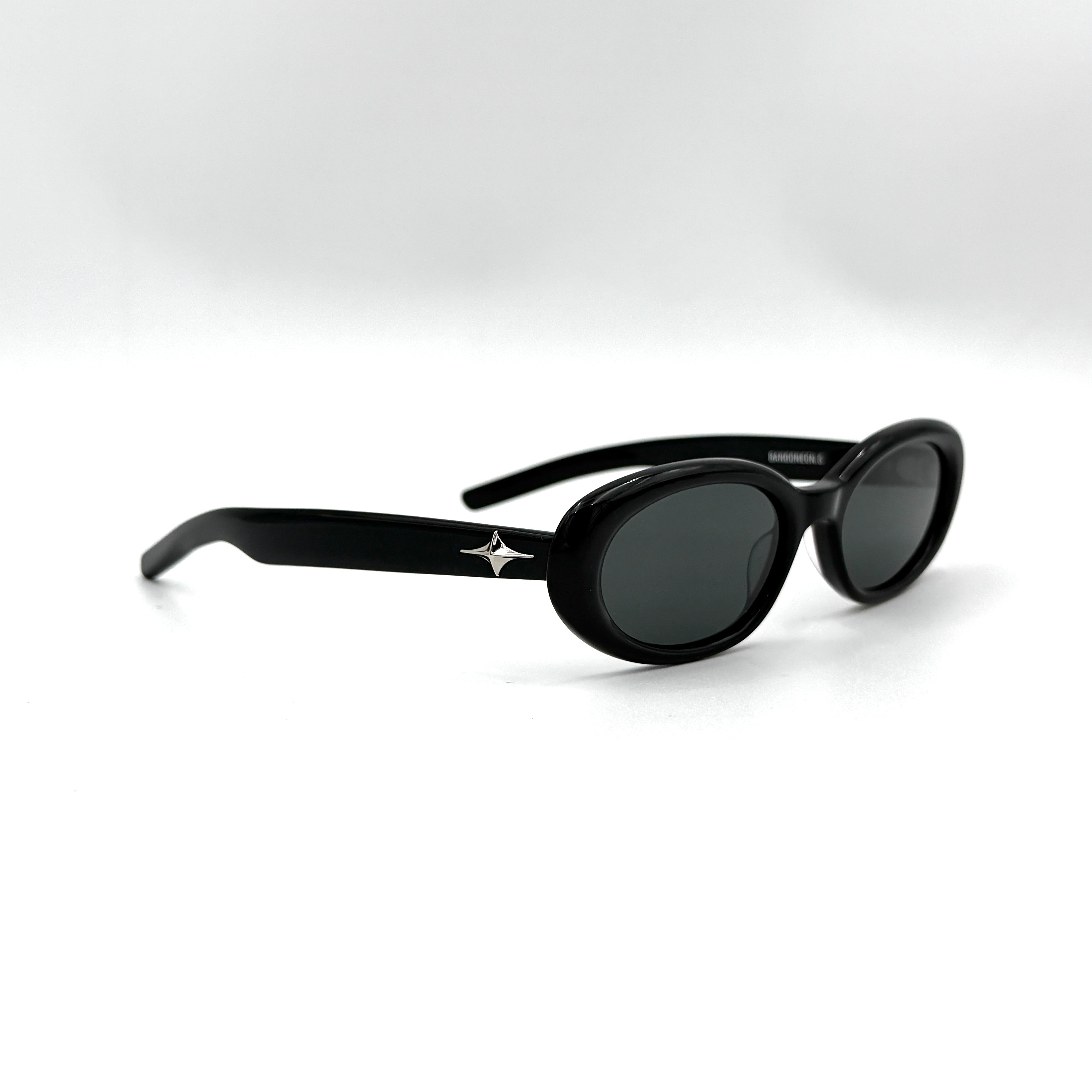 Gentle Monster Bandoneon.S sunglasses in black acetate with dark oval lenses and silver star accents shown from the side.