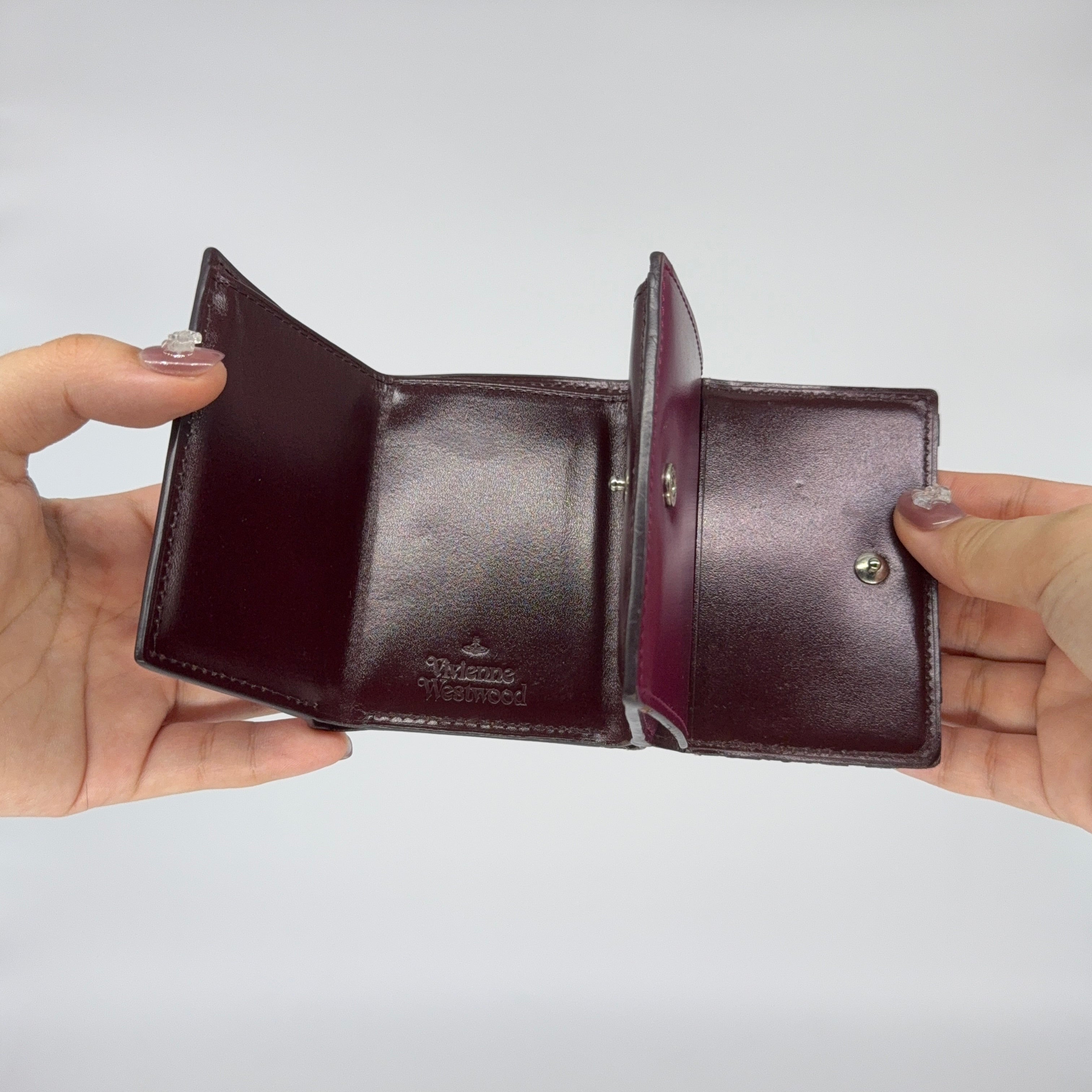 Vivienne Westwood Signature Orb Wallet in glossy purple leather with silver orb emblem on the front flap.