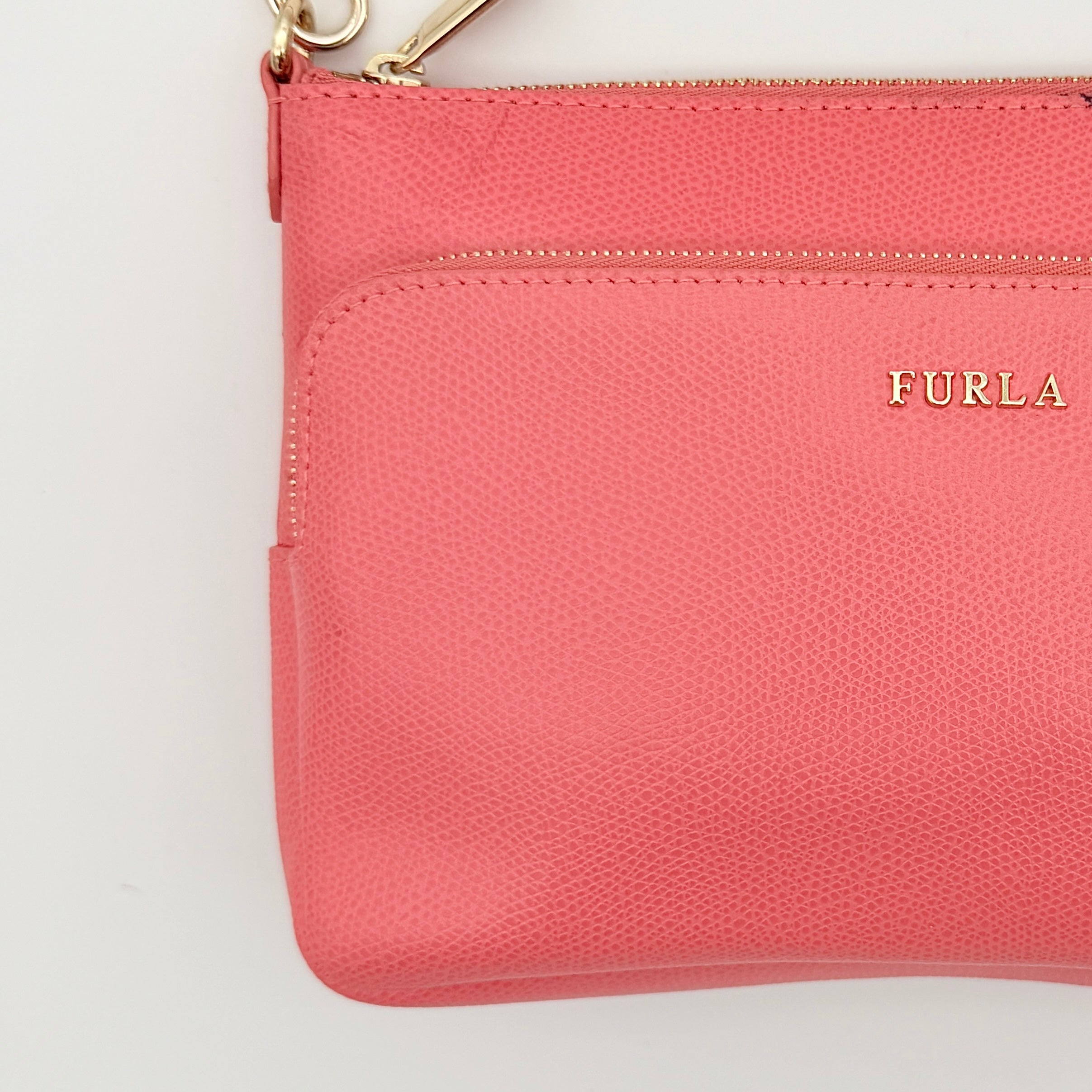 Furla pink leather crossbody bag with gold zip and adjustable strap, photographed flat on a white background.