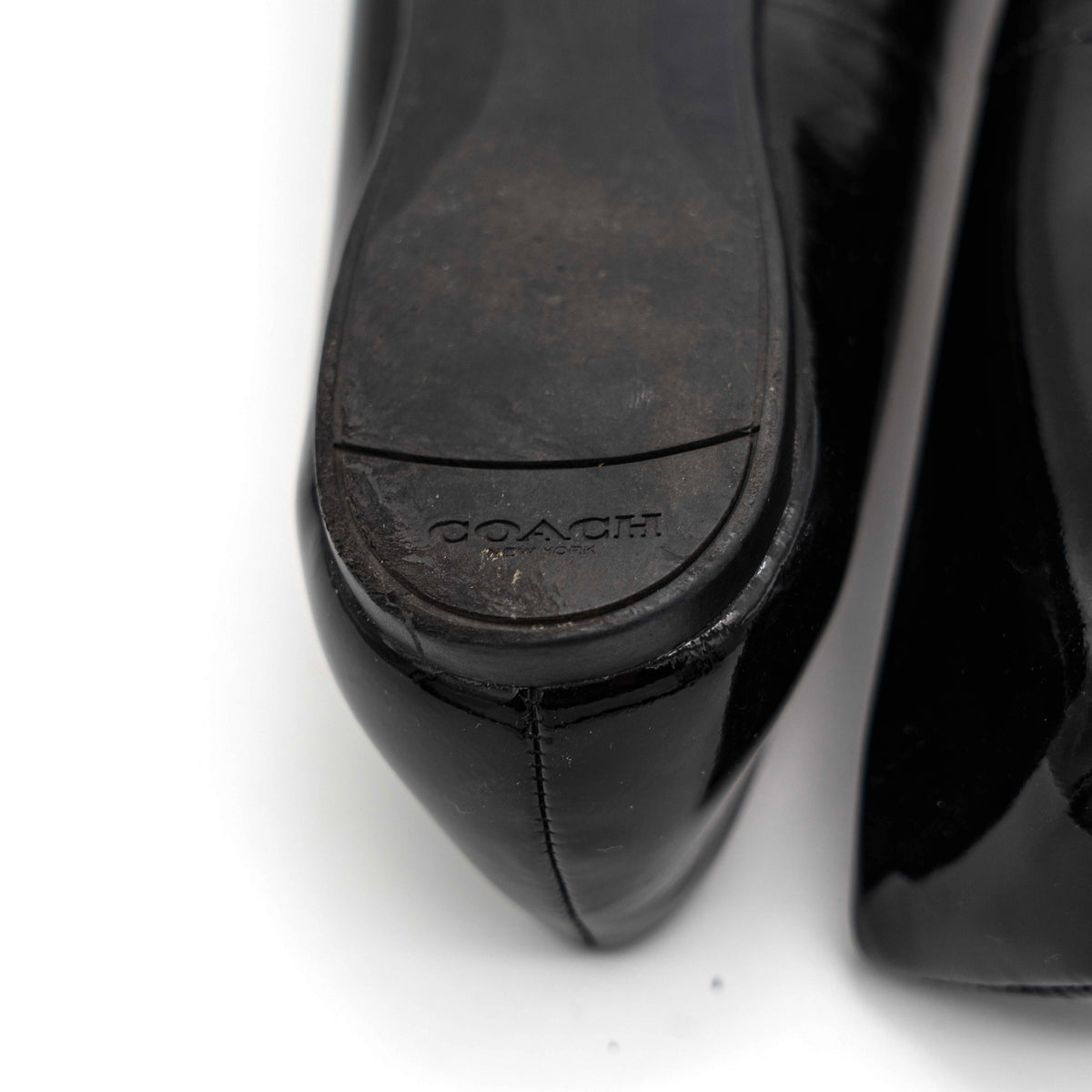 Coach Oswald Turnlock black patent leather ballet flats with dark metal hardware on the toe, photographed on a white background.