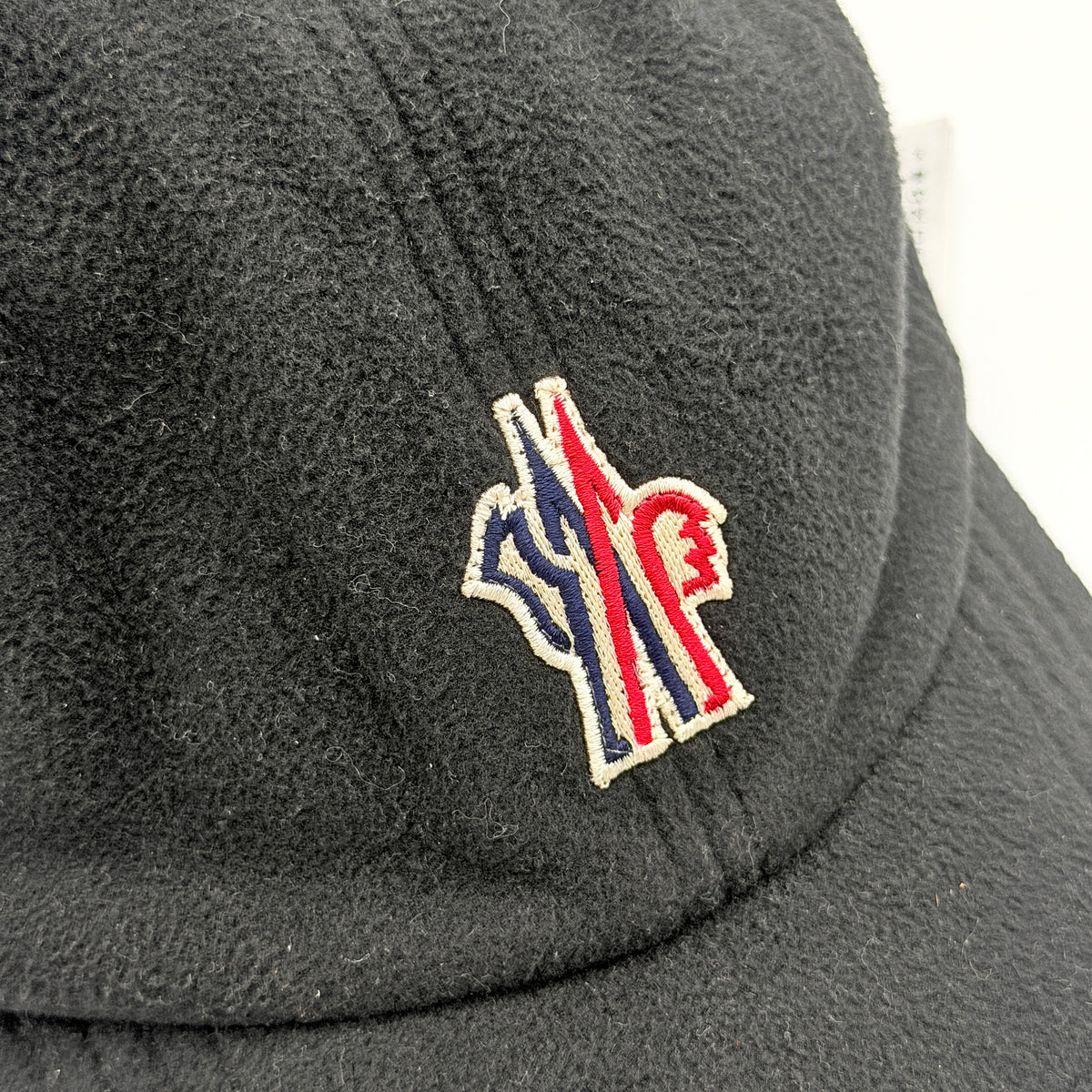 Moncler Grenoble black fleece baseball cap with tri-colour logo patch on the front and tonal embroidery details.