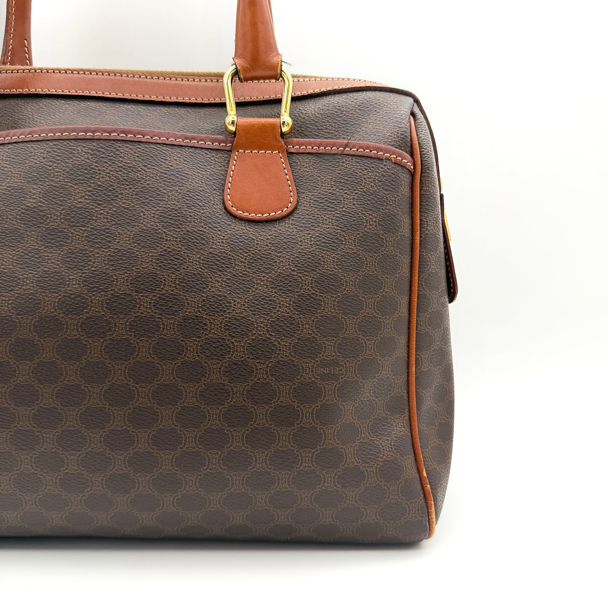Celine Triomphe Macadam Boston Bag in brown coated canvas with tan leather handles and gold hardware on a white background.