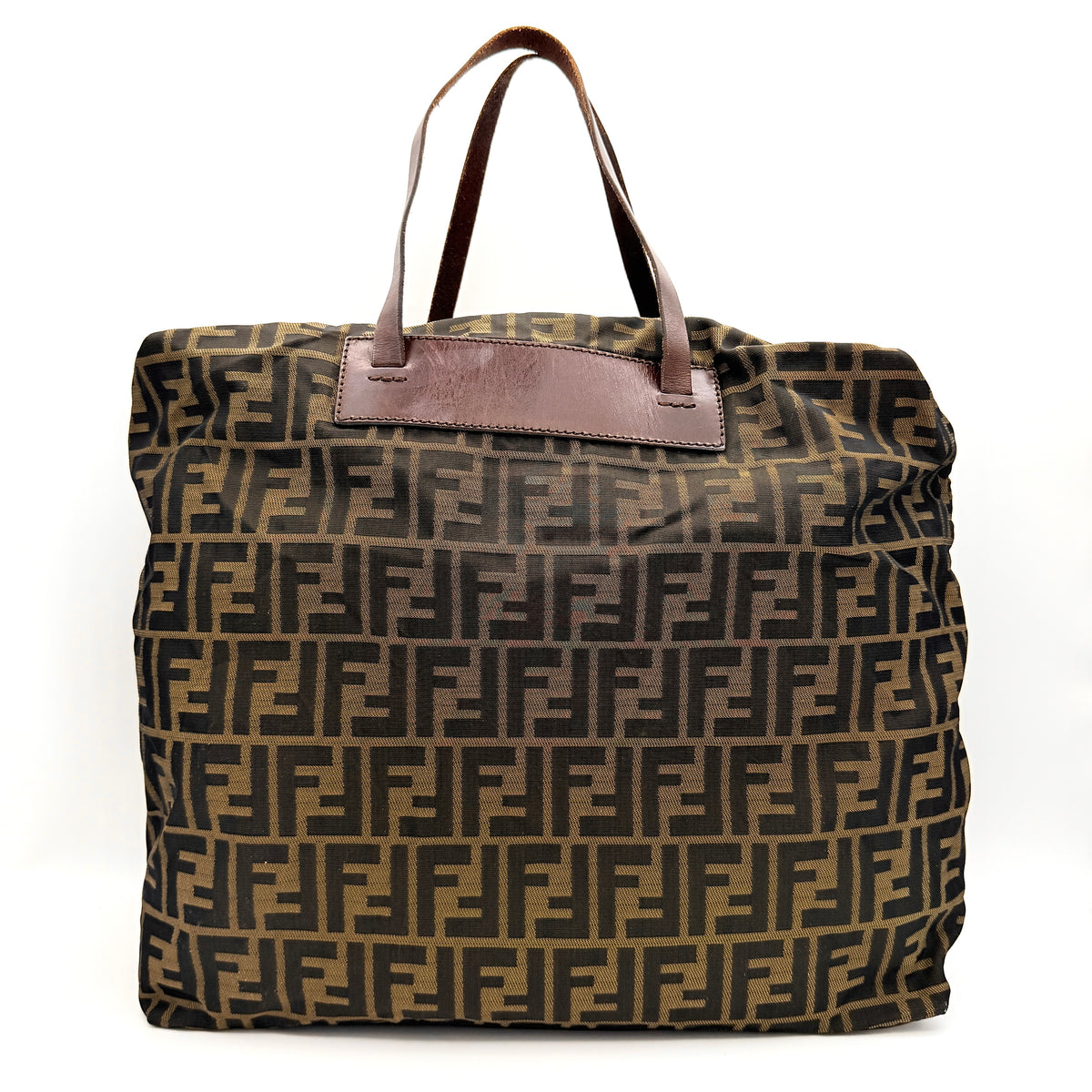 Fendi FF Zucca foldable tote bag in brown canvas with leather top handles and all-over monogram, shown standing upright.