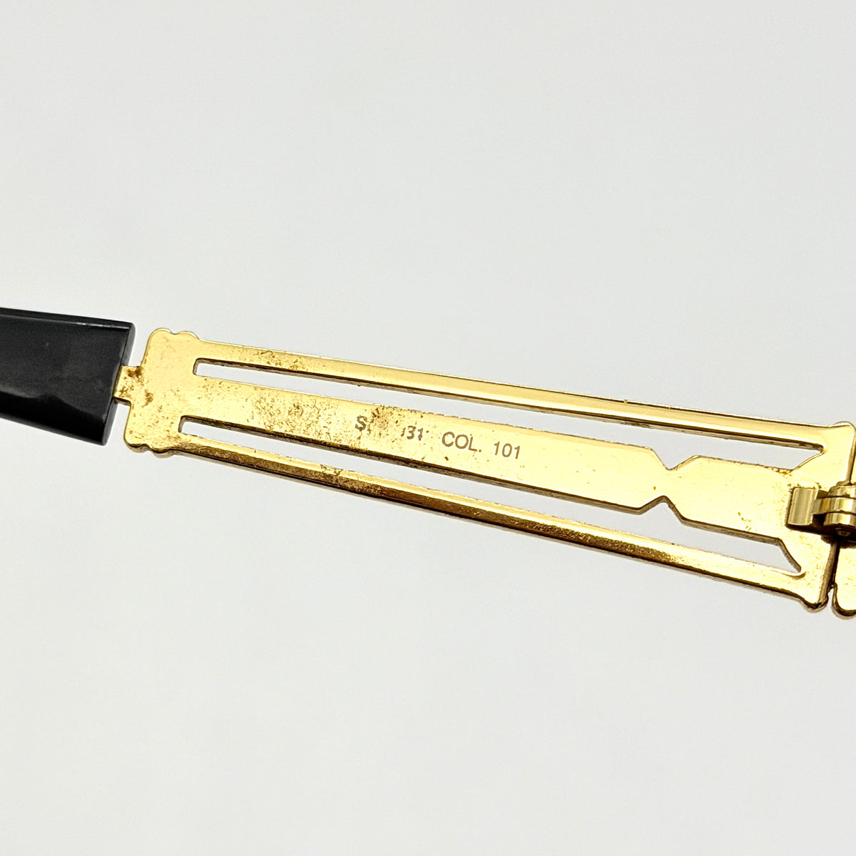 Fendi FF SL7031 oval sunglasses with gold-tone frame, brown lenses, and black arms, shown at an angled side view.