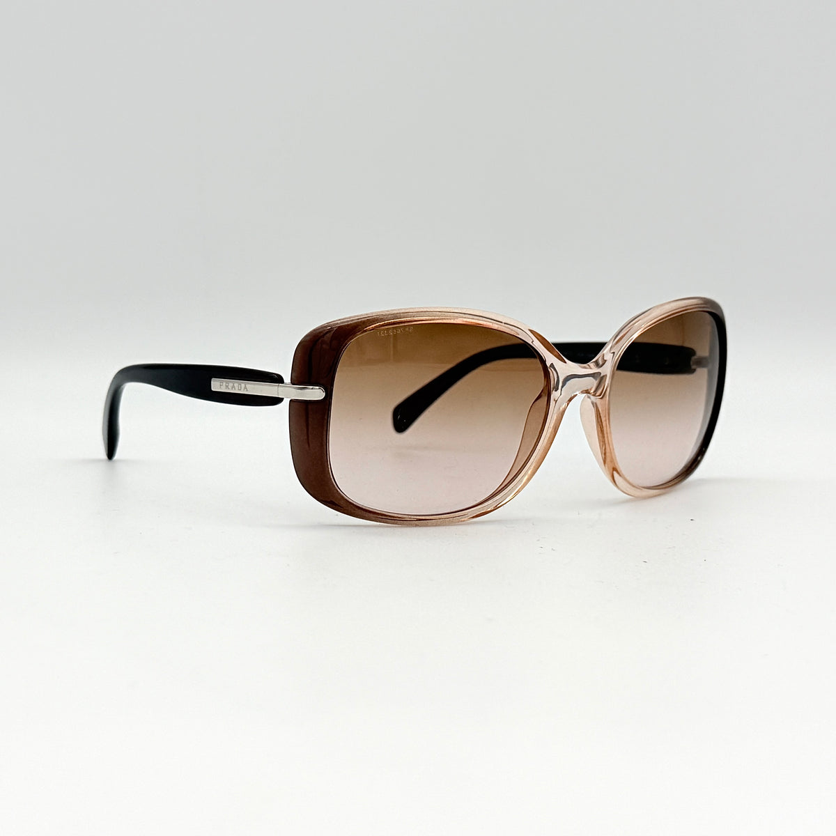 Prada SPR080 sunglasses featuring a brown and blush oversized frame with gradient lenses and silver hardware at the temples.