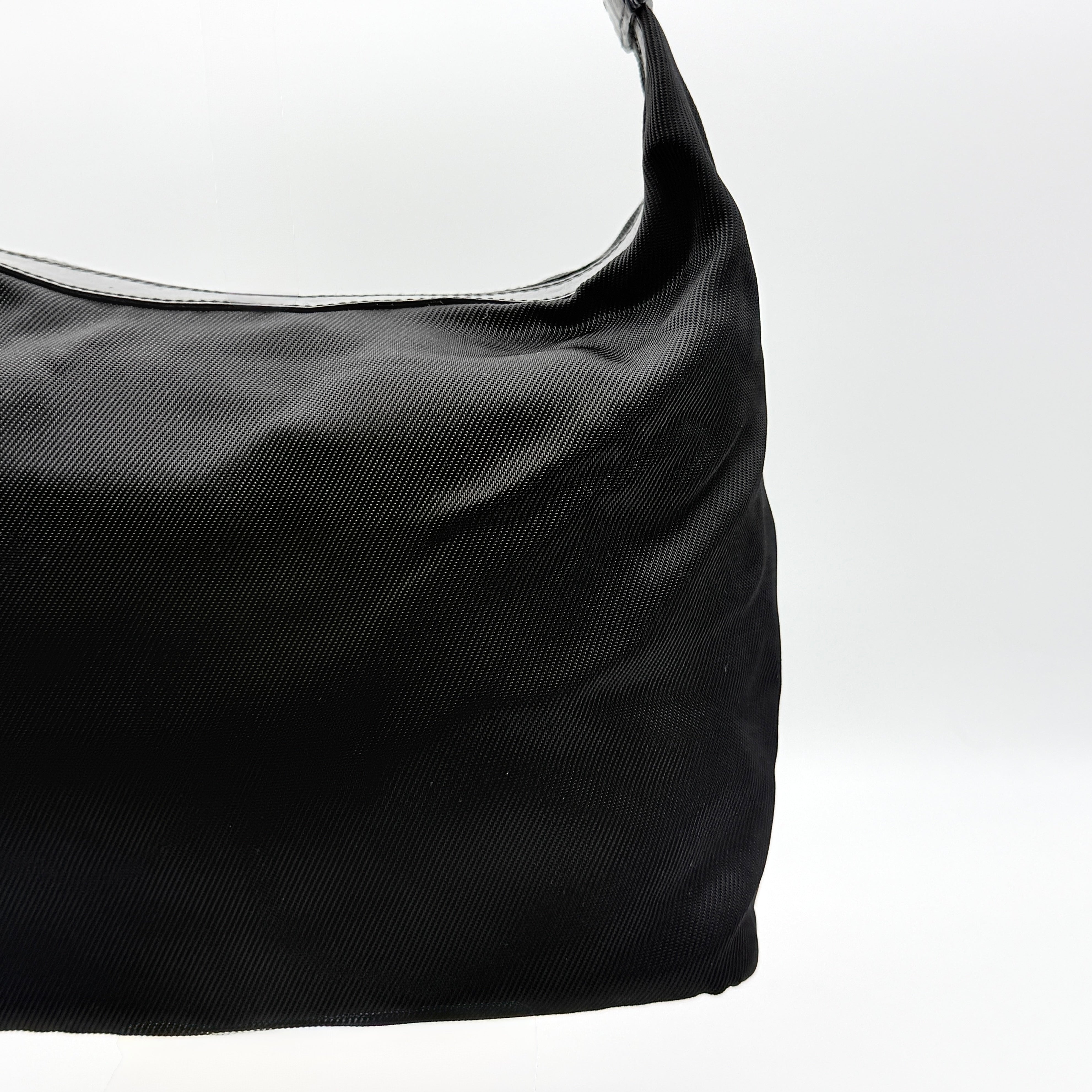 Gucci black nylon shoulder bag with bamboo handle and leather trim, photographed against a white background.