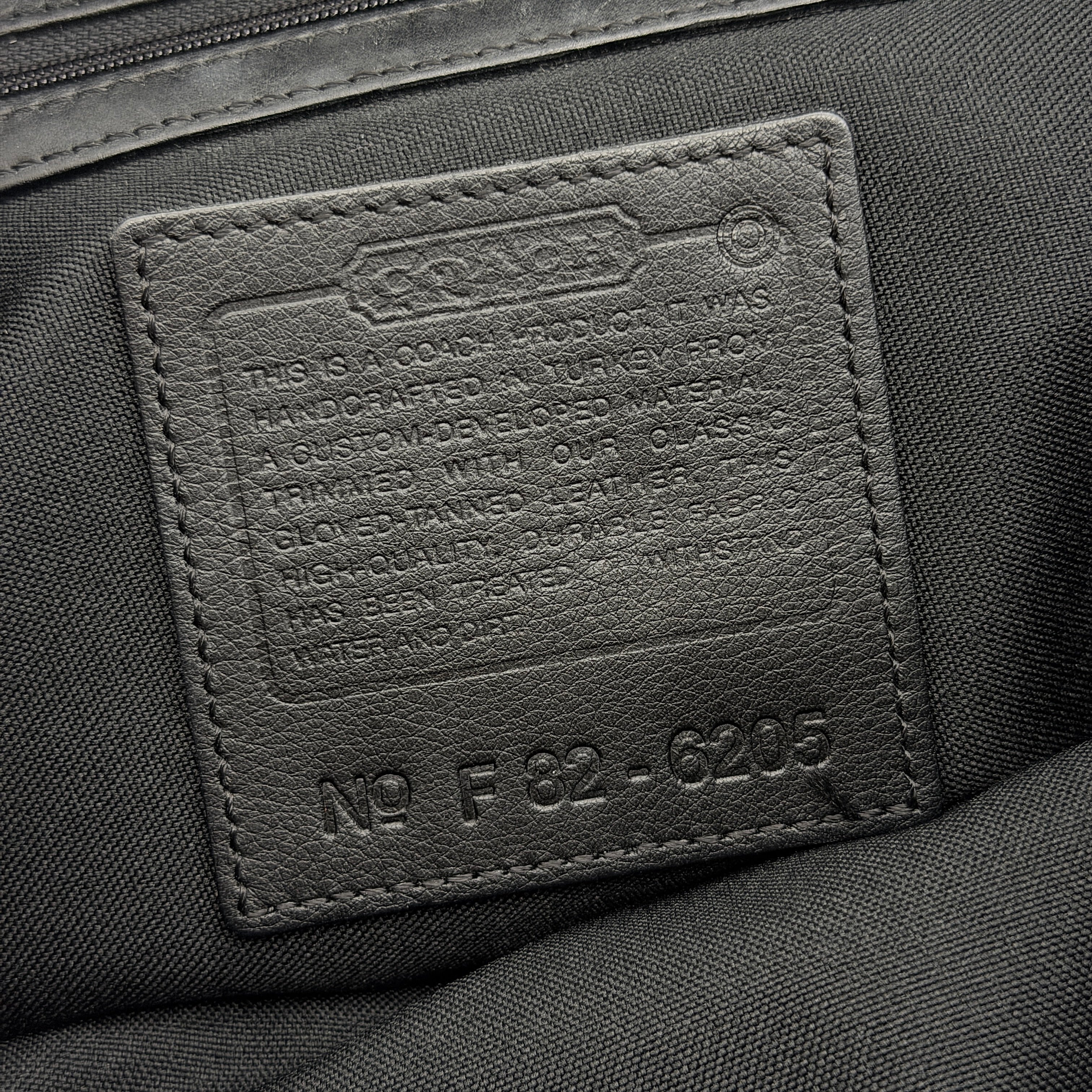 Coach brown neoprene drawstring backpack with leather trim, silver-tone hardware, and adjustable straps shown against a white background.