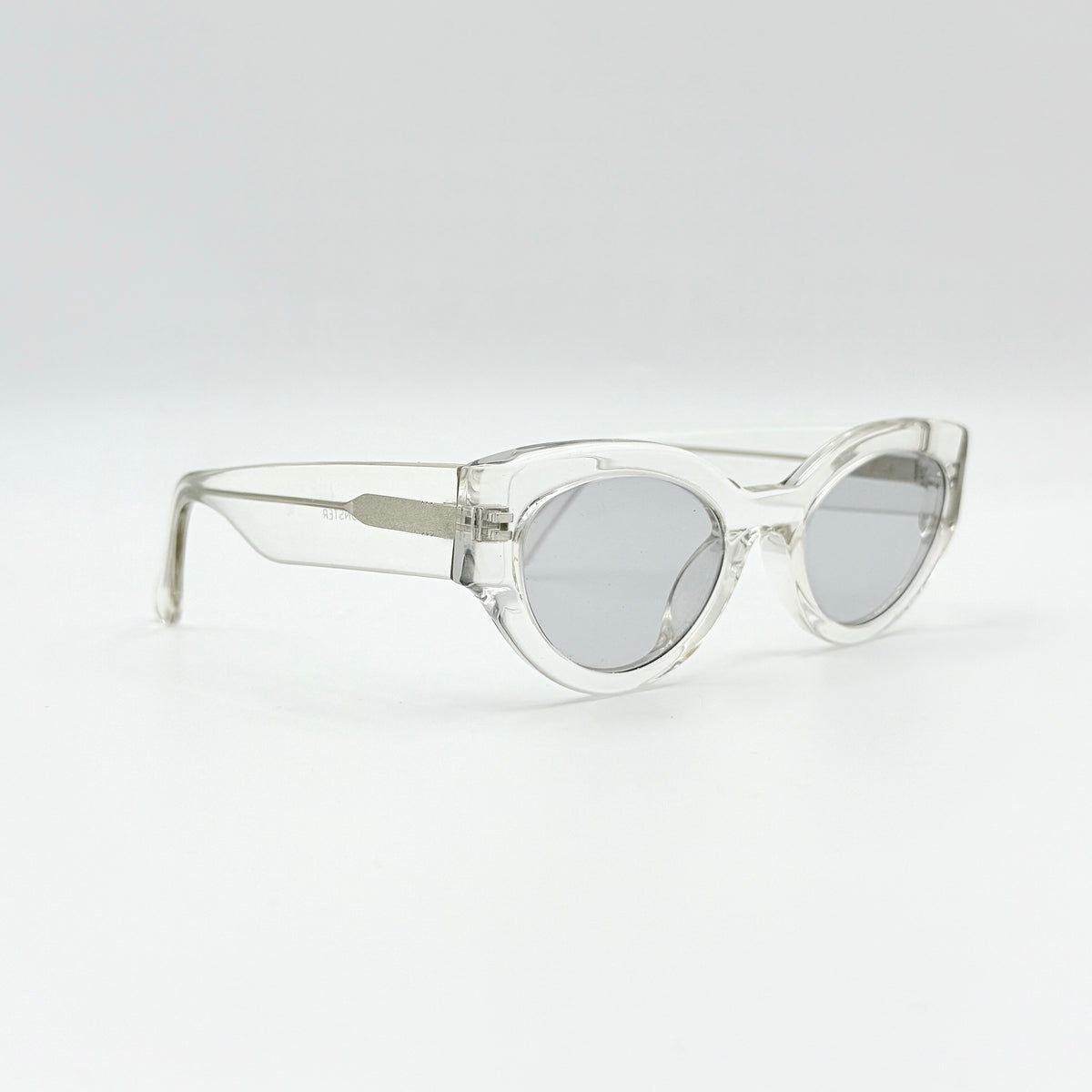 Gentle Monster Tazi transparent sunglasses with grey lenses and clear acetate frame, softly styled alongside the branded case.
