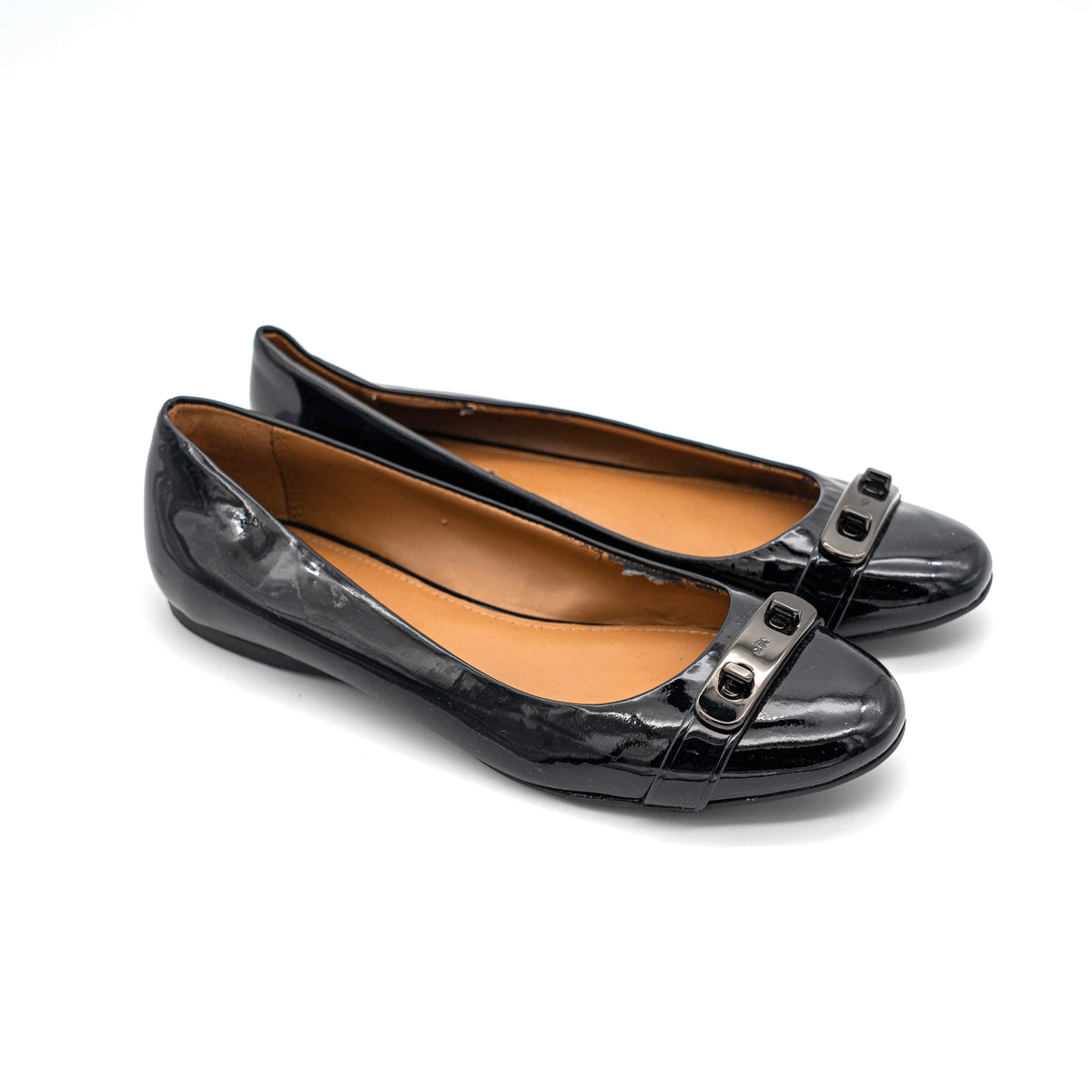 Coach Oswald Turnlock black patent leather ballet flats with dark metal hardware on the toe, photographed on a white background.