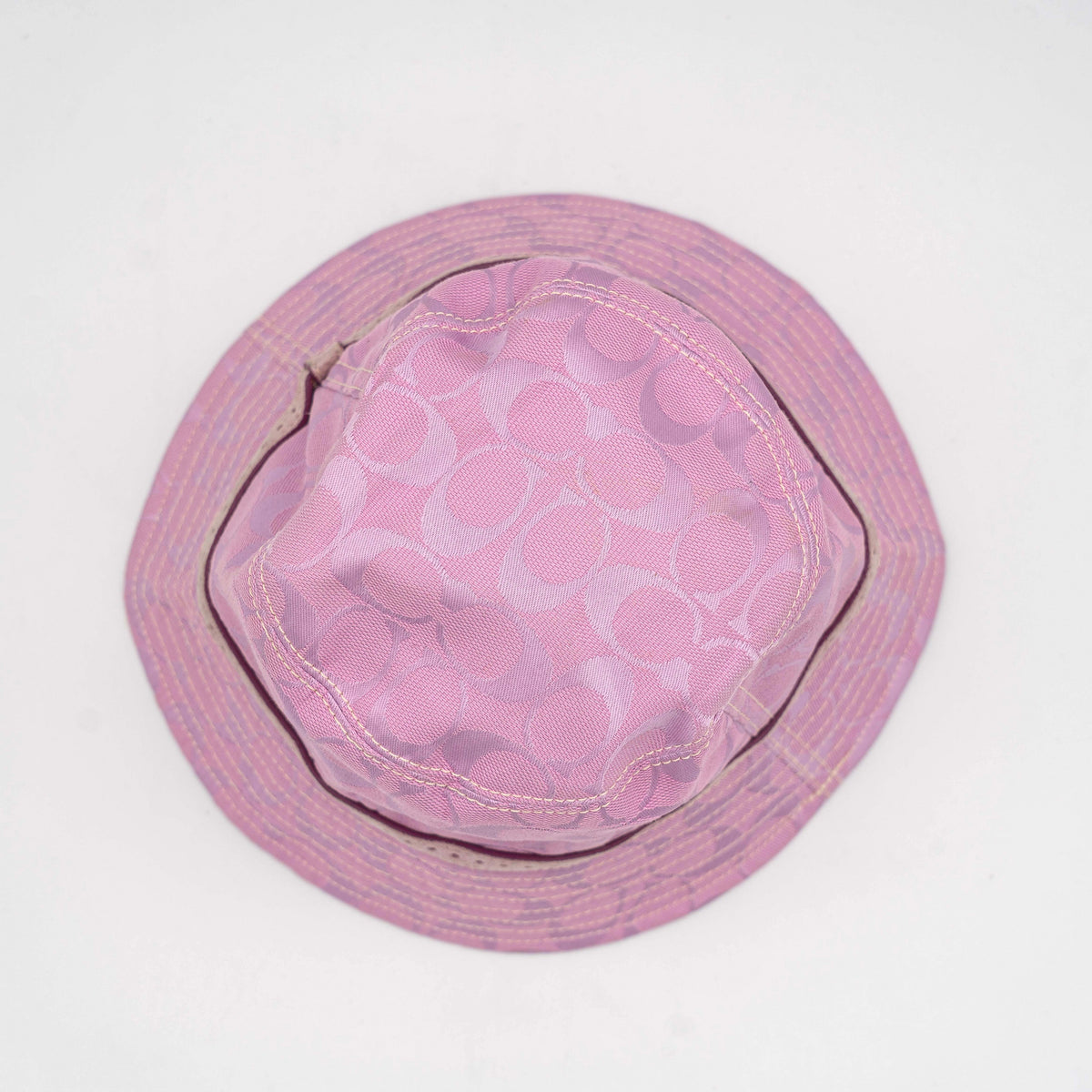 Coach pink jacquard bucket hat with taupe suede-effect band, shown against a neutral background.