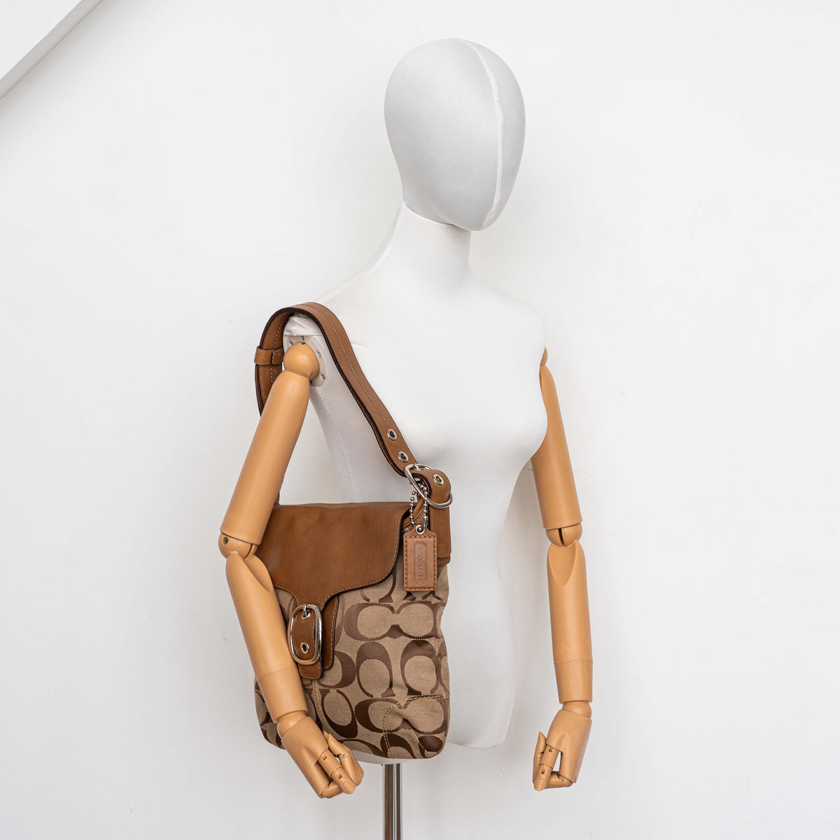Coach 2Way Signature Soho Buckle Flap Shoulder Bag in beige and tan with silver buckle and adjustable leather strap, shown on a white background.