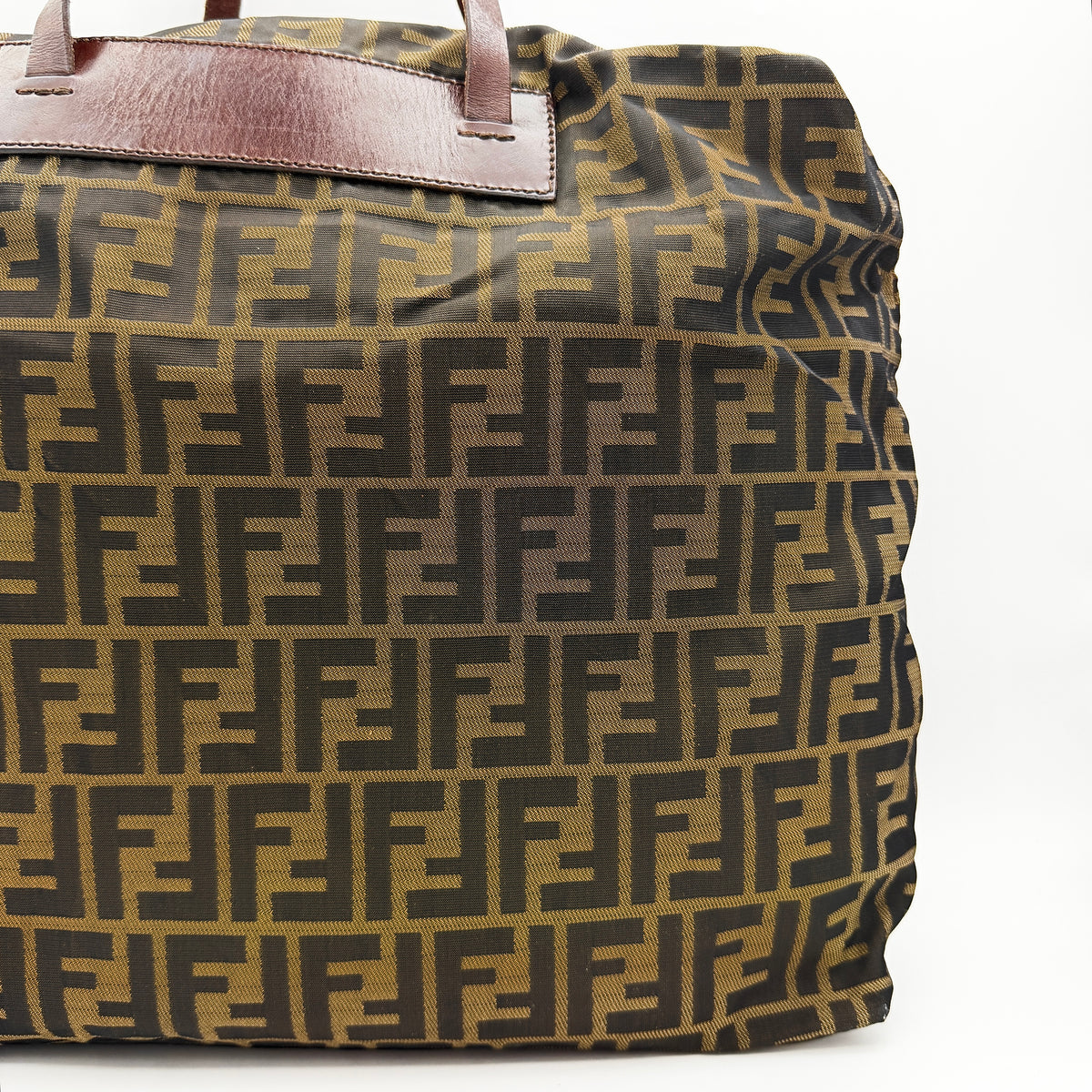 Fendi FF Zucca foldable tote bag in brown canvas with leather top handles and all-over monogram, shown standing upright.