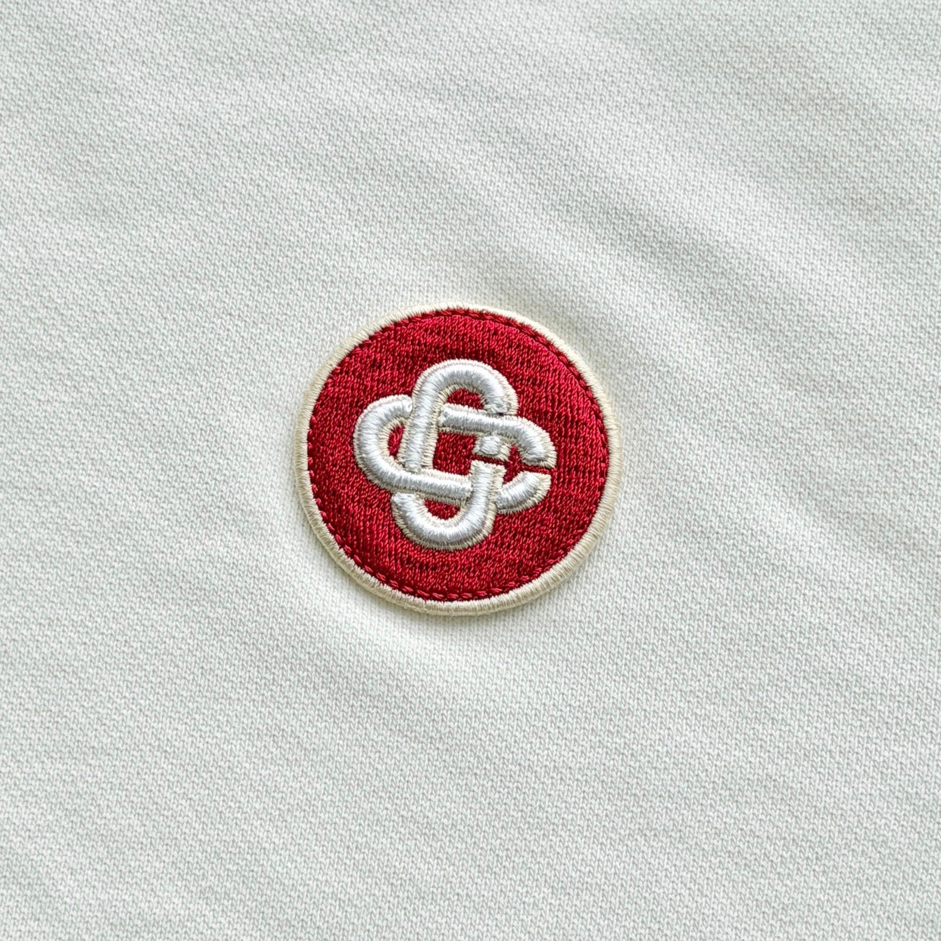 Casablanca off-white hoodie with a red logo patch and kangaroo pocket, laid flat and showing the front view.