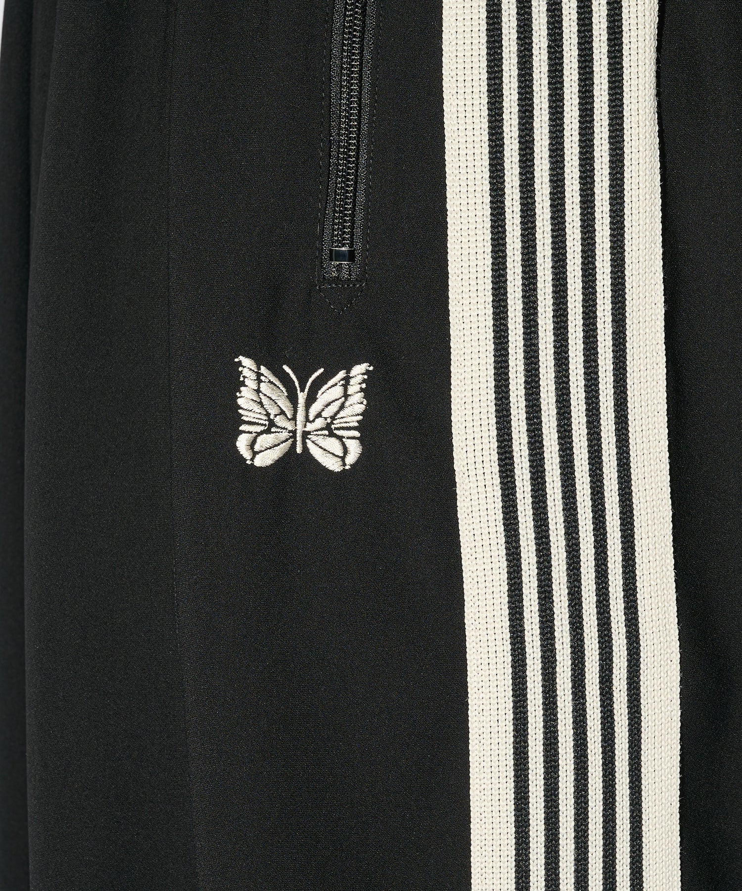 Needles H.D. Track Pant in black with white stripes and butterfly logo, shown in a full-length styled view.