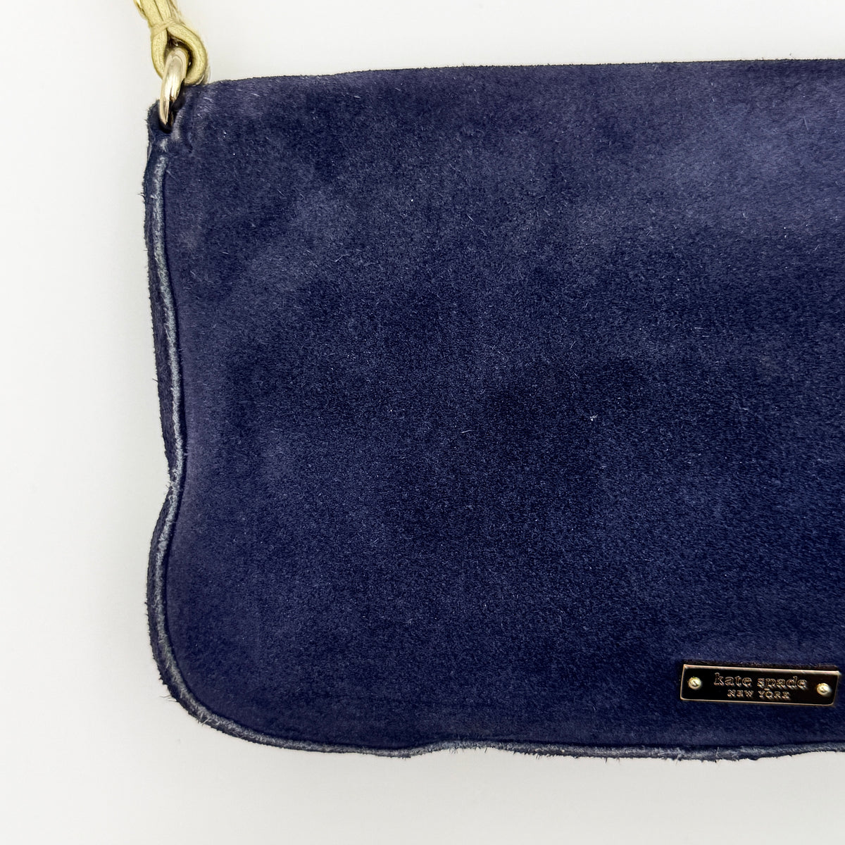 Navy blue suede Kate Spade baguette bag with floral gold hardware and gold-tone shoulder strap.