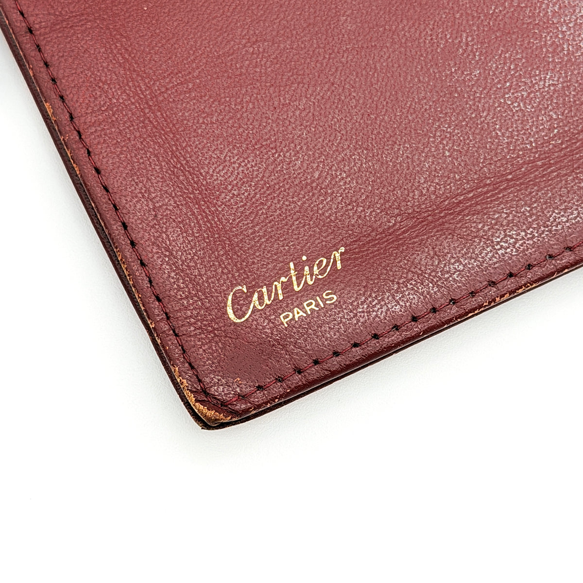 Cartier Must de Cartier burgundy leather bifold long wallet with embossed logo and organized interior compartments.
