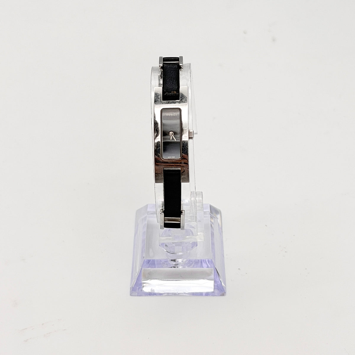 Gucci 3900L black dial watch with silver-tone rectangular case and black leather strap displayed on a stand