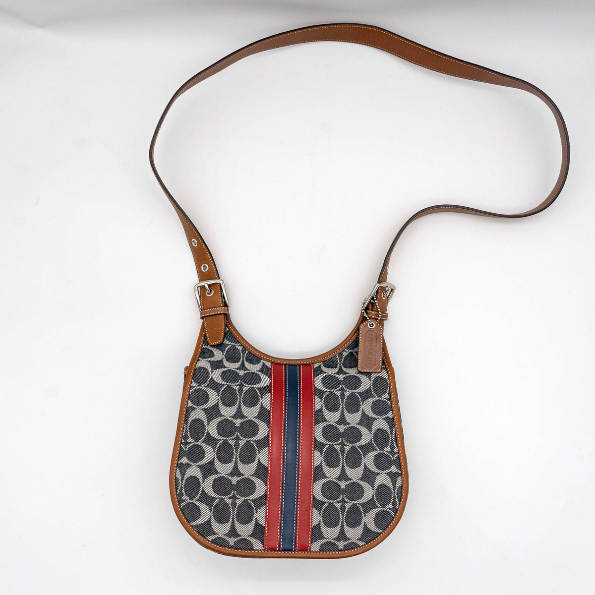 Coach signature denim hobo crossbody bag with red and blue stripe, brown leather trim, and an adjustable strap.