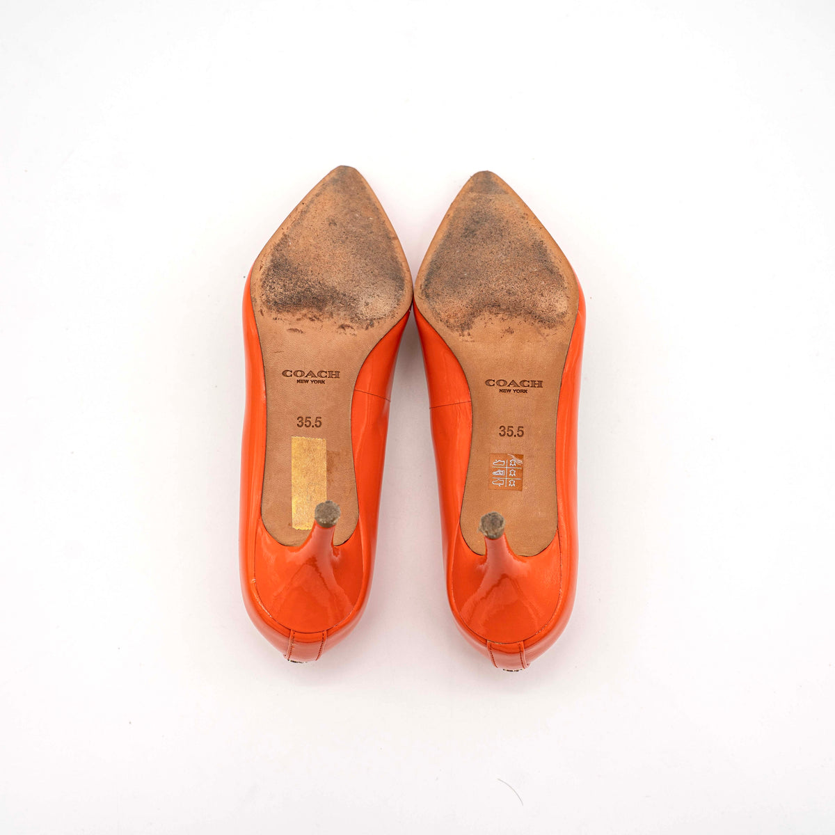 Pair of Coach orange patent leather pointed-toe heels with gold logo detail, size EU 35.5.