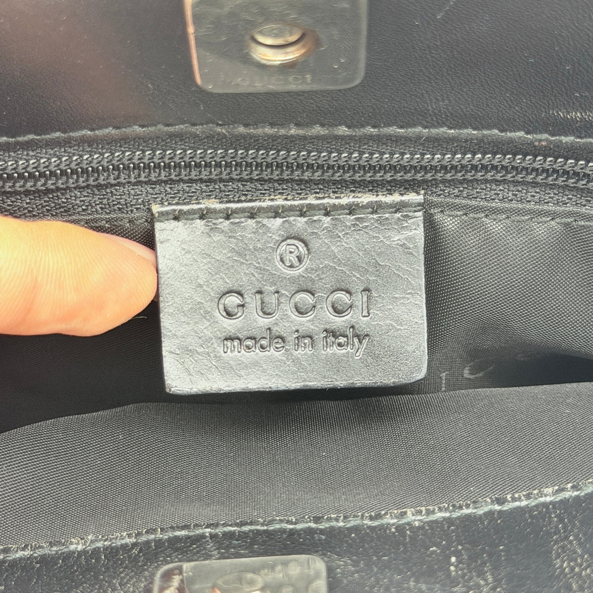 Front view of the Gucci black nylon tote with dual zip pockets and leather top handles.