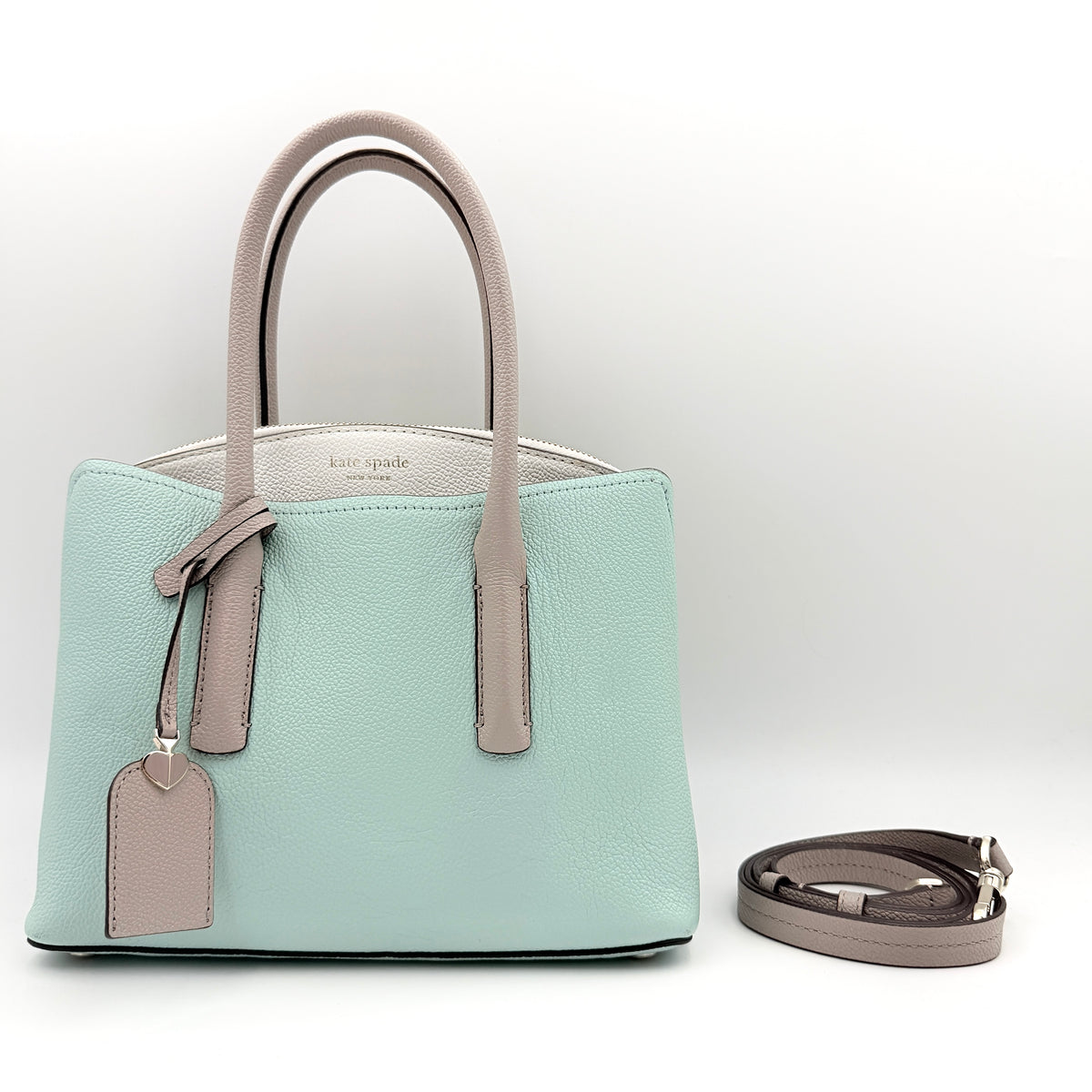 Kate Spade New York Margaux satchel in mint green pebbled leather with taupe handles, shown with its detachable strap and a clear pouch.