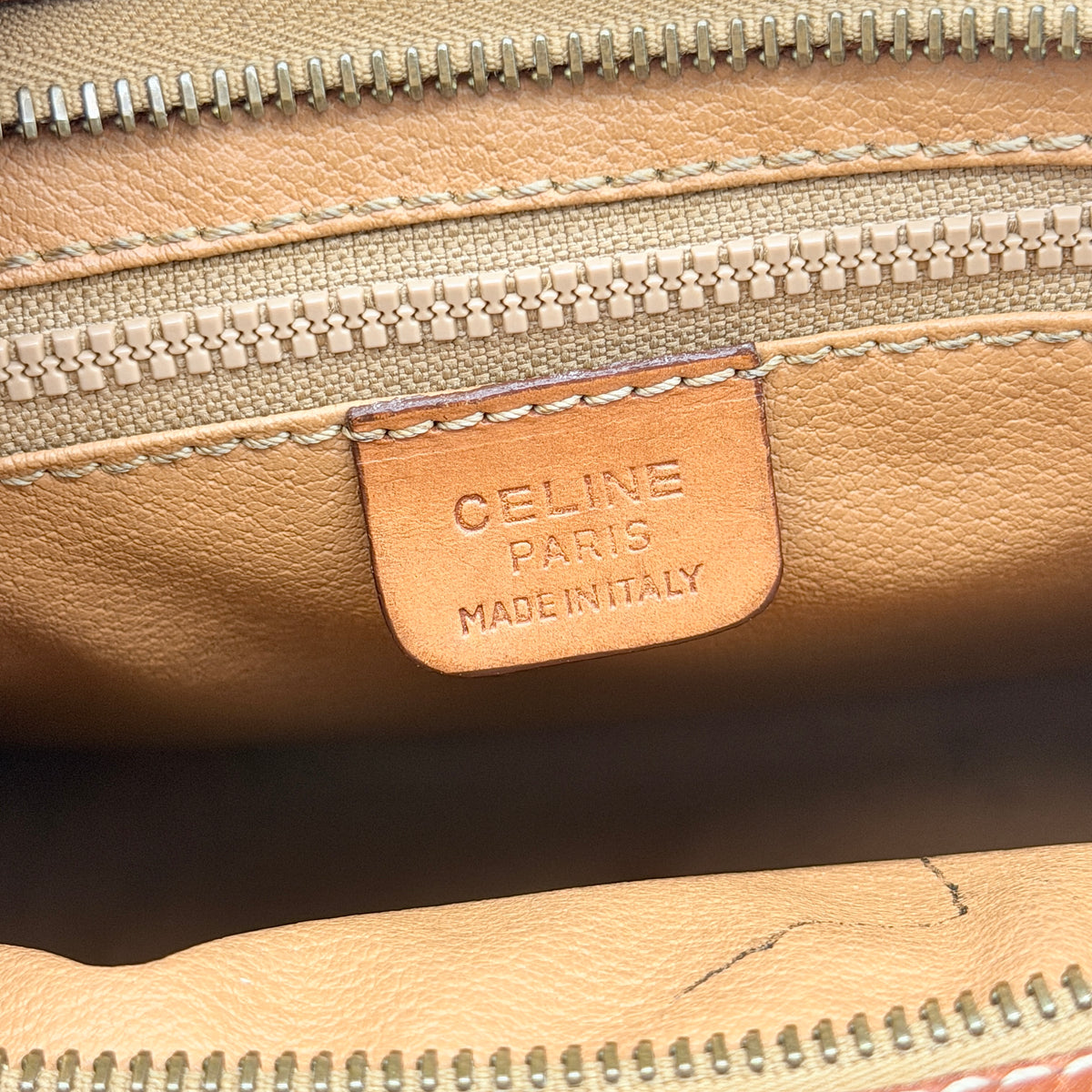 Celine Triomphe Macadam clutch bag in brown canvas with tan leather trim and gold hardware, shown with wrist strap.