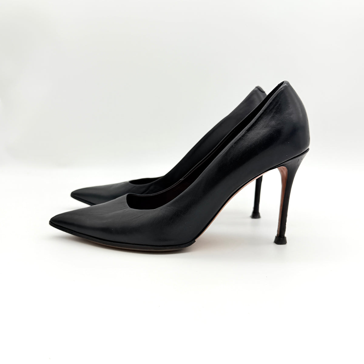 A pair of black leather Celine stiletto heels with pointed toes and burgundy insoles, shown in a softly lit studio setting.