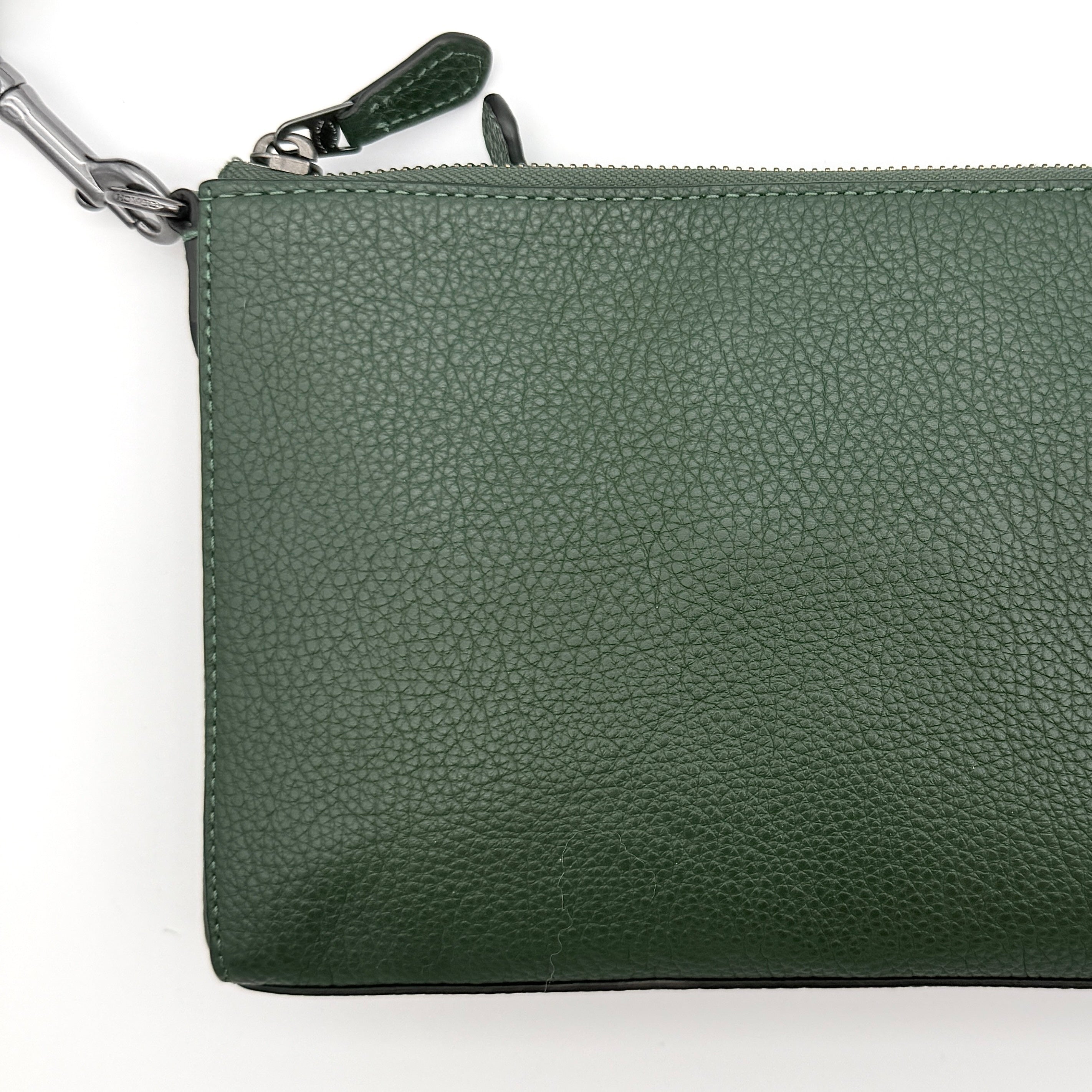 Coach Holden Crossbody bag in dark green pebbled leather with adjustable black webbing strap, displayed against a white background.