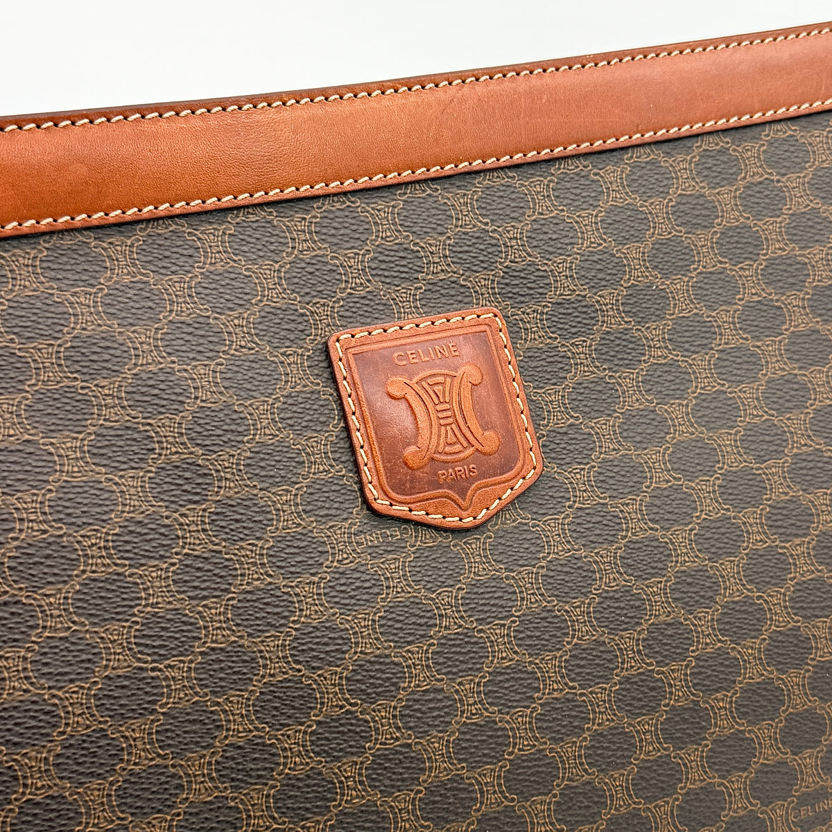 Celine Triomphe Macadam Clutch Bag in brown coated canvas with leather trim, shown against a white background.
