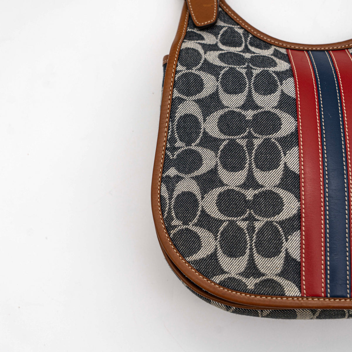 Coach signature denim hobo crossbody bag with red and blue stripe, brown leather trim, and an adjustable strap.