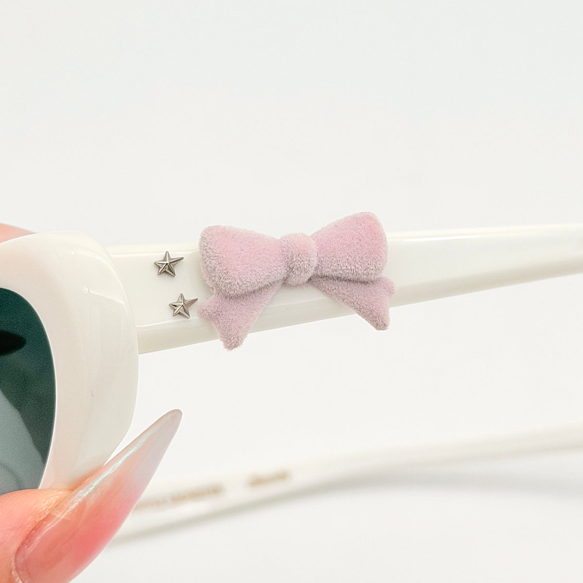 Gentle Monster x Jennie Hush W2 oval sunglasses in white with a pink bow charm, styled with the signature pink furry case.