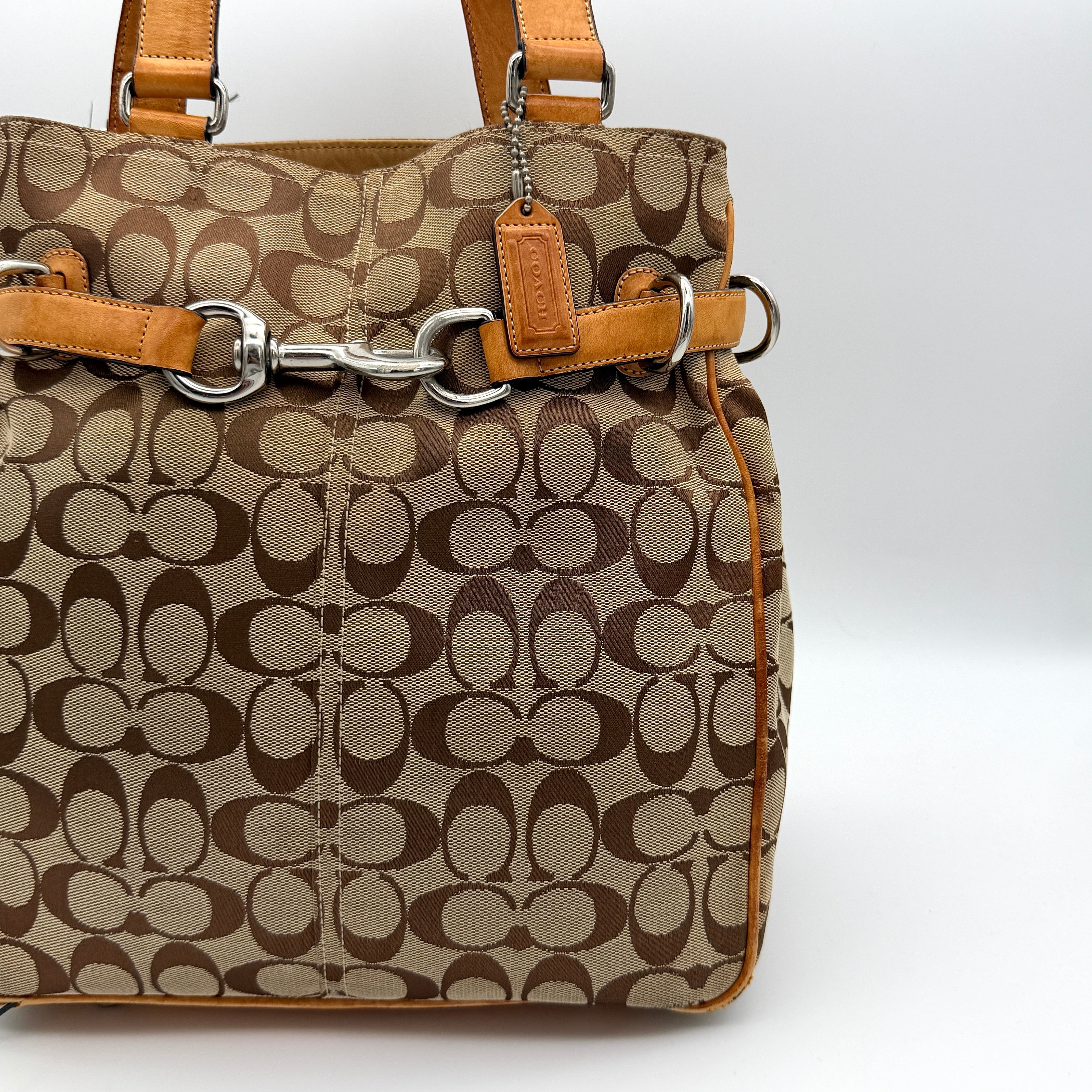Coach Signature Buckle Tote Bag in beige and tan with signature canvas, tan leather trim, and silver-tone hardware.