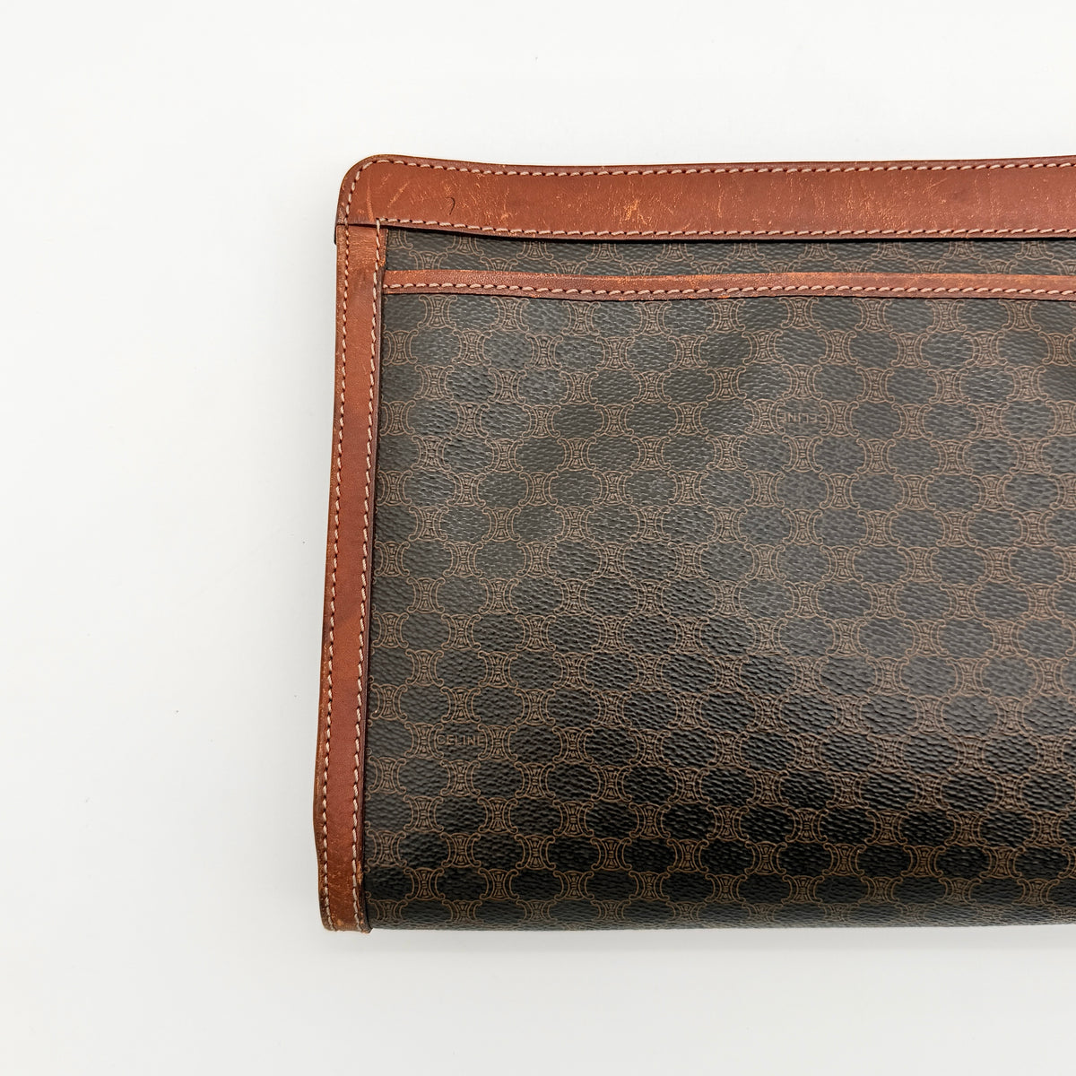 Celine Triomphe Macadam clutch bag in brown canvas with tan leather trim and gold hardware, shown with wrist strap.