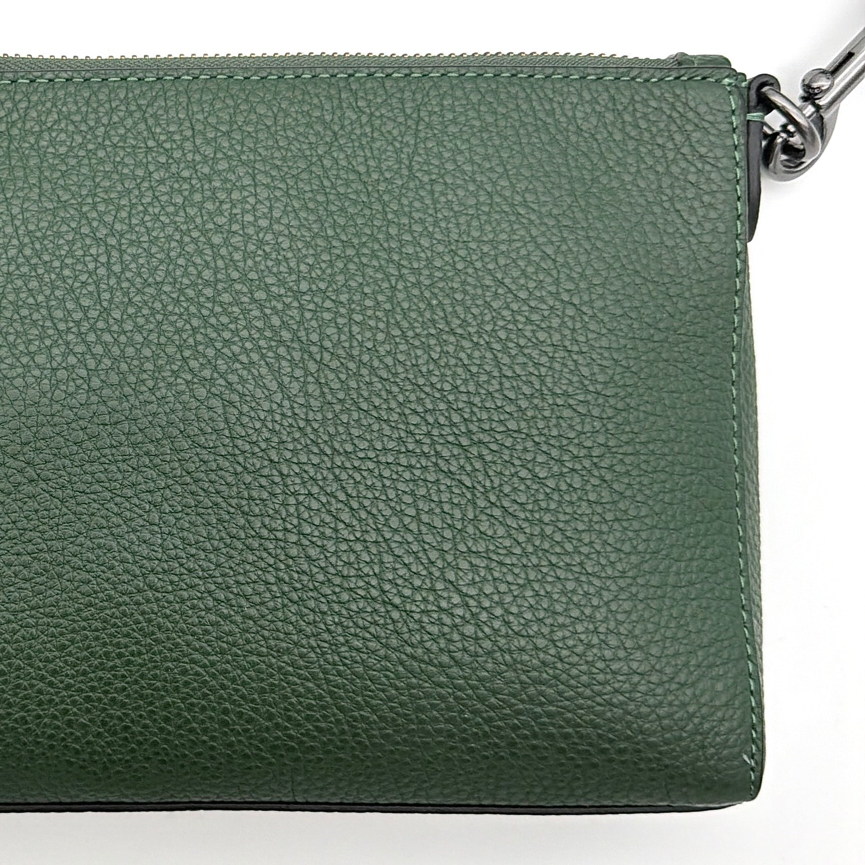 Coach Holden Crossbody bag in dark green pebbled leather with adjustable black webbing strap, displayed against a white background.