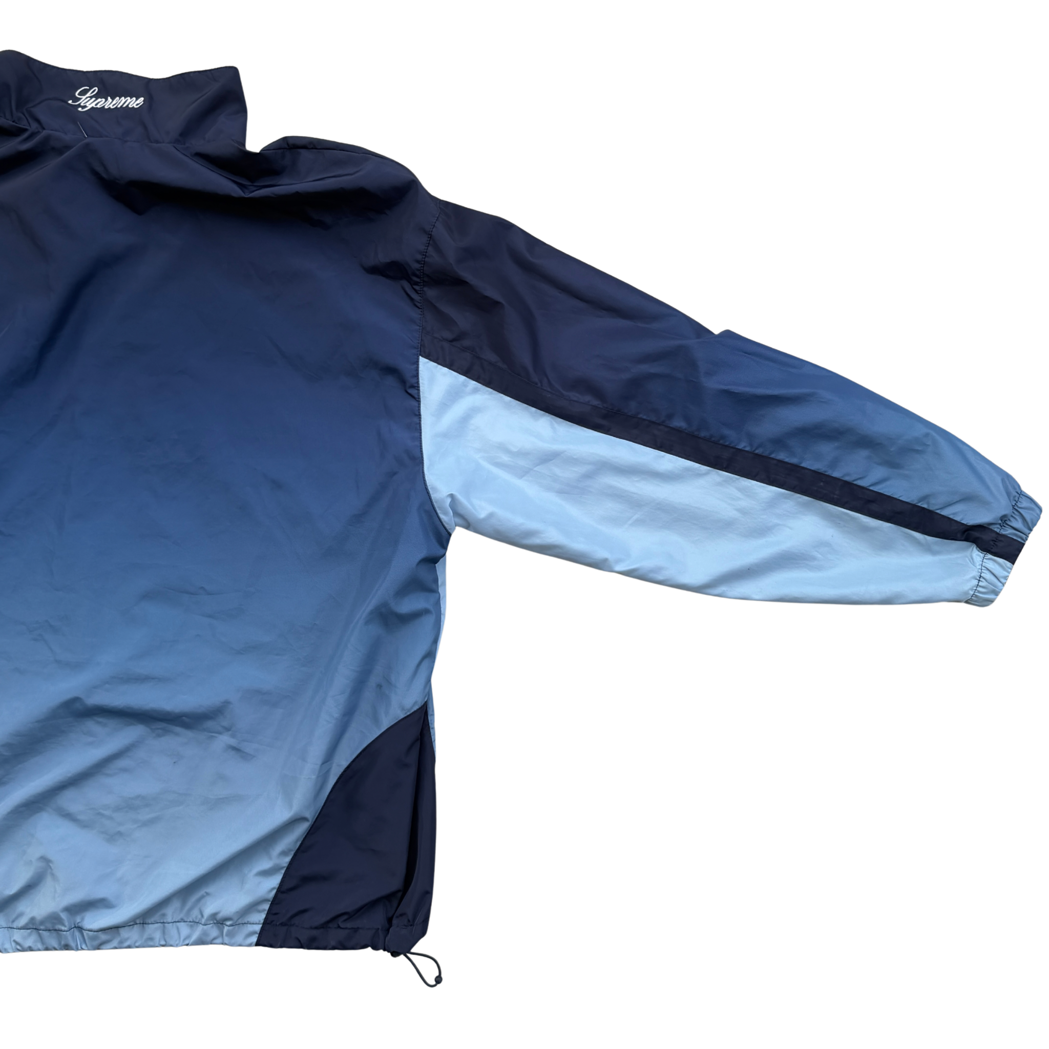 Supreme x Umbro blue gradient track jacket with white Supreme Champions lettering and crest, shown zipped with elastic cuffs and hem.