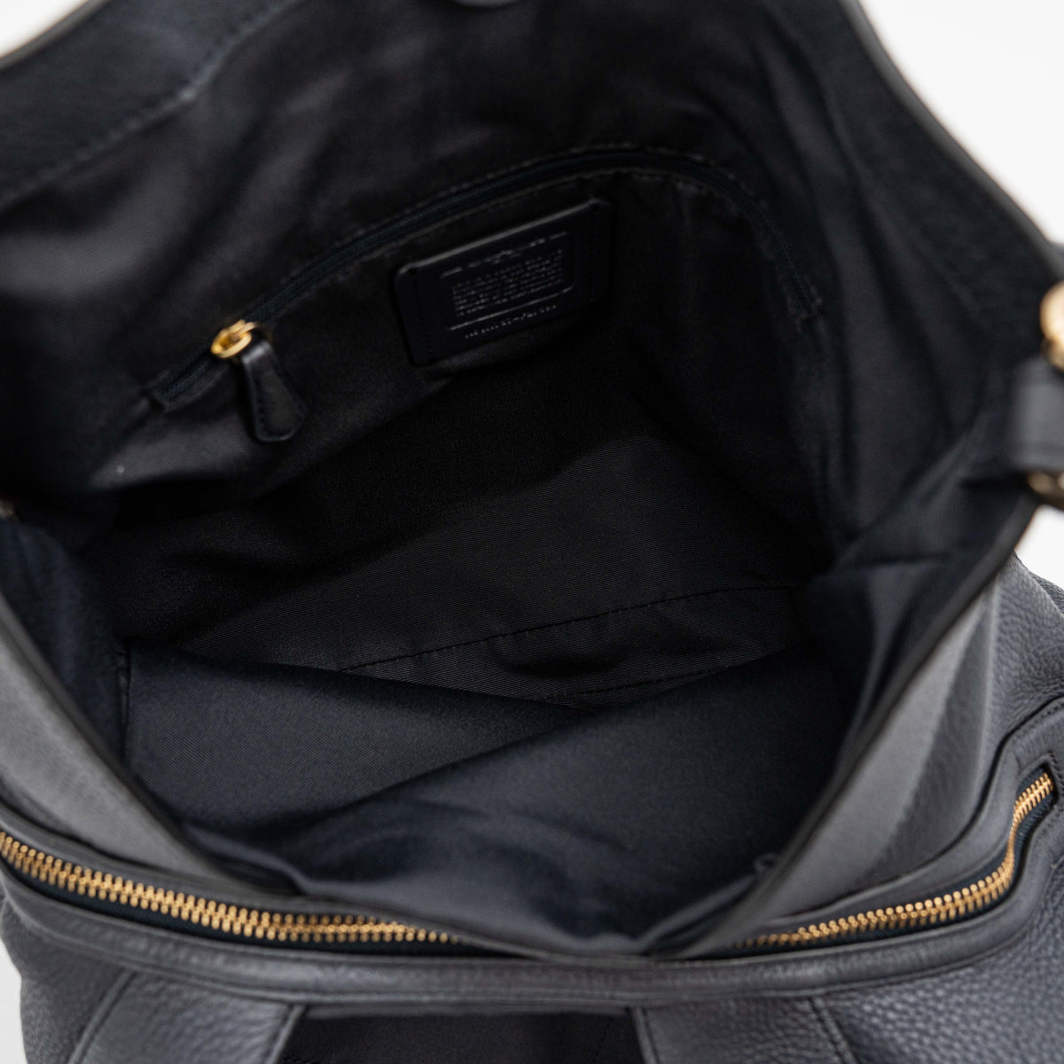 Coach Lexy Shoulder Bag in black pebbled leather with gold-tone hardware and double handles, styled against a white background.