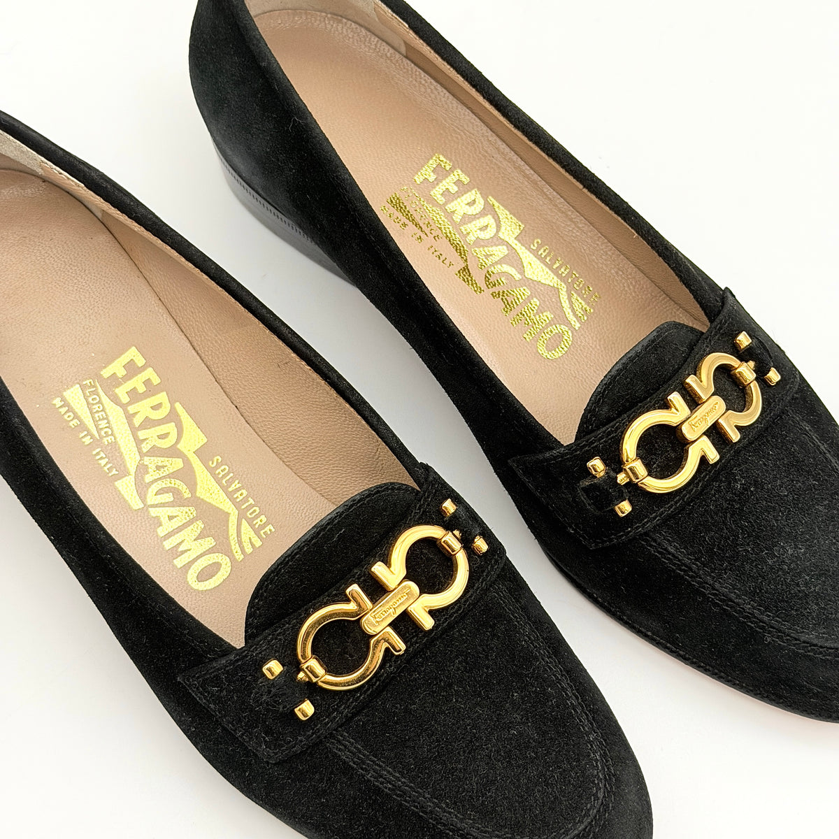 Salvatore Ferragamo black suede loafers with gold Gancini horsebit detail, displayed side by side on a white background.