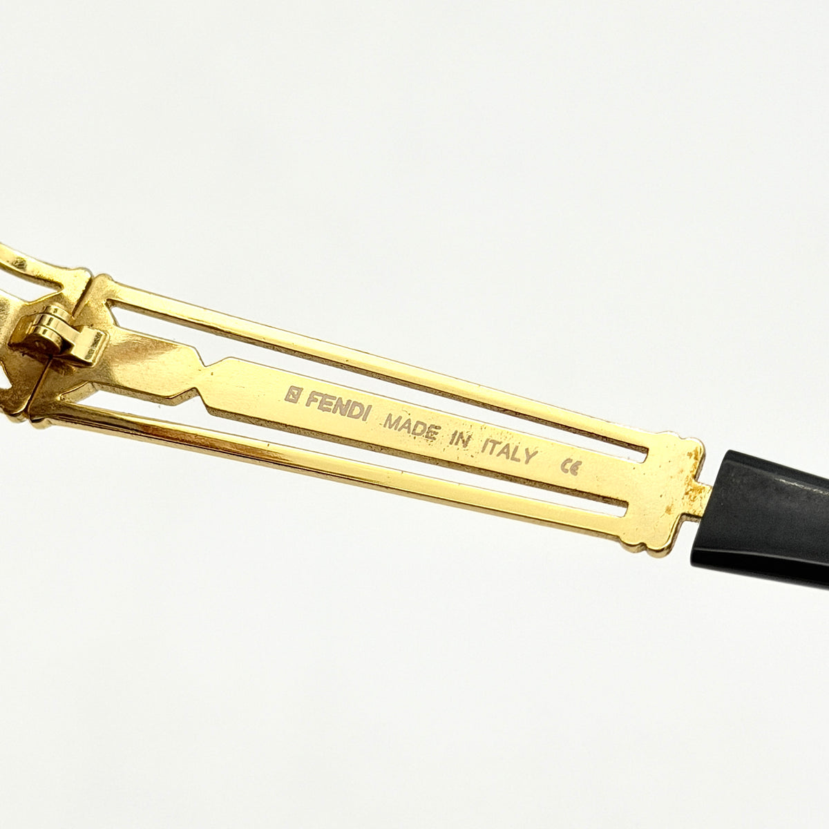 Fendi FF SL7031 oval sunglasses with gold-tone frame, brown lenses, and black arms, shown at an angled side view.