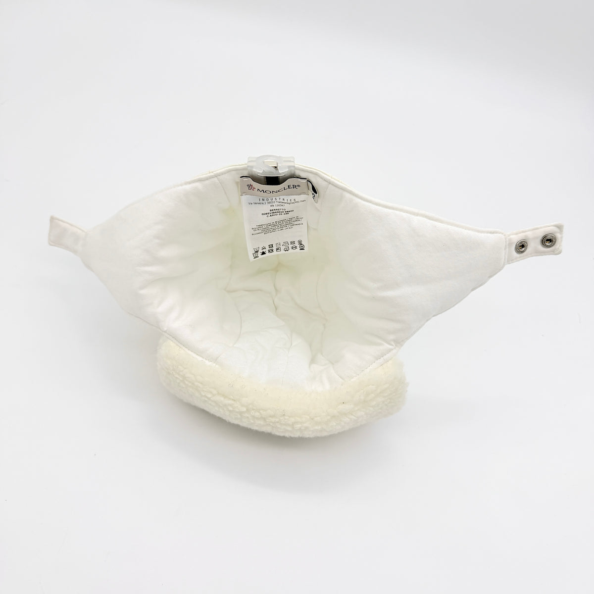 Moncler ivory quilted trapper hat with plush faux fur trim and signature logo patch displayed on white background.