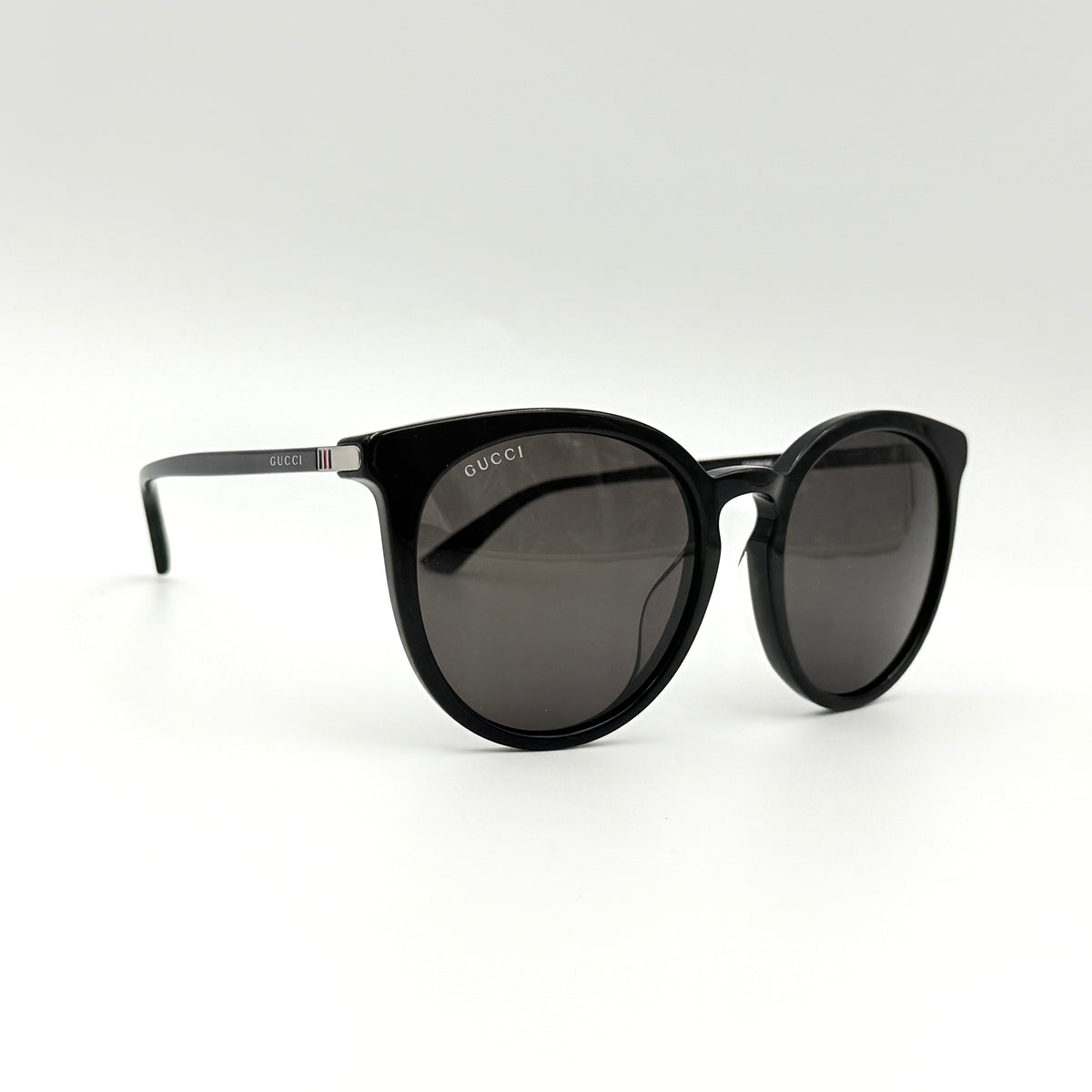 Gucci GG0064SK 001 black round sunglasses with smoky lenses, shown with original burgundy velvet case and pouch.