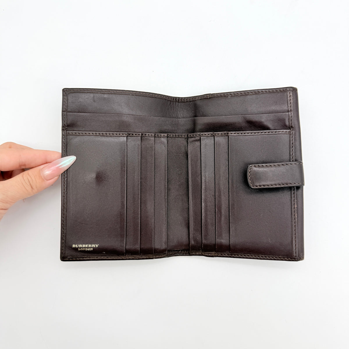 Burberry Nova Check wallet in beige and brown with leather trim and brass buckle detail photographed on white background.