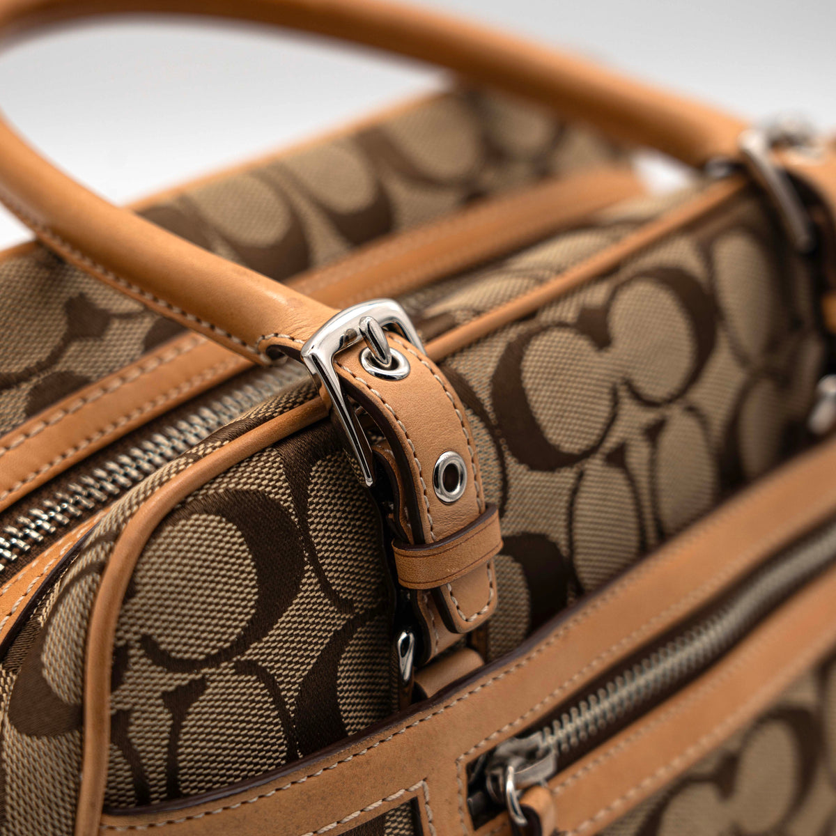Coach Signature Hampton Satchel Boston Bag in beige and tan canvas with leather trim and silver hardware, styled on a clean background.