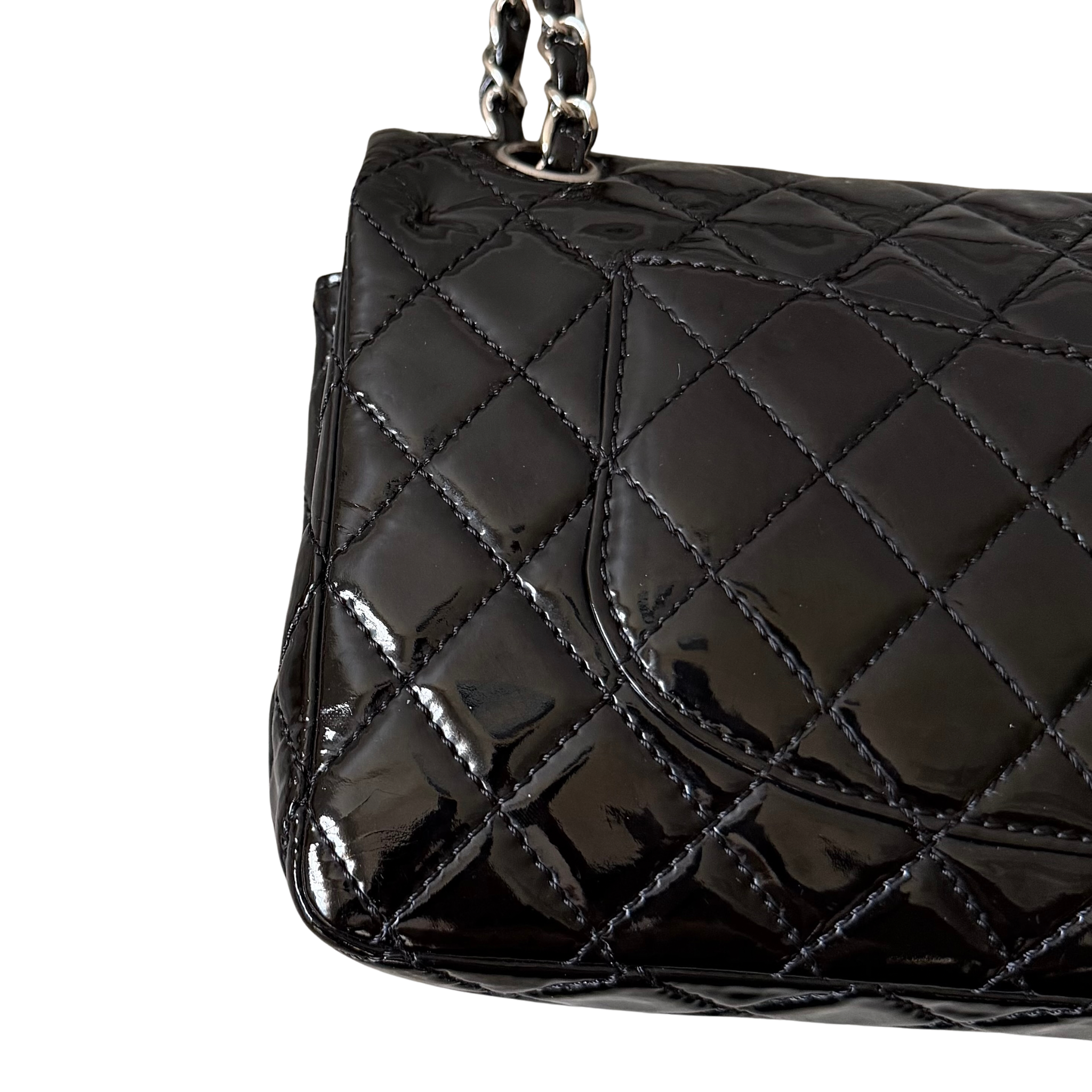 Chanel 25 Matelasse Double Flap bag in glossy black patent leather with silver-tone hardware and quilted finish.