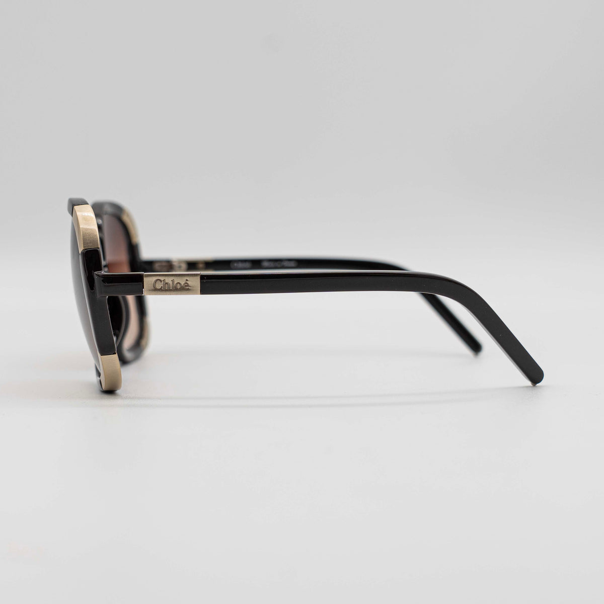Chloé CL2119 sunglasses in black with gold-tone accents and brown gradient lenses, displayed at an angle.