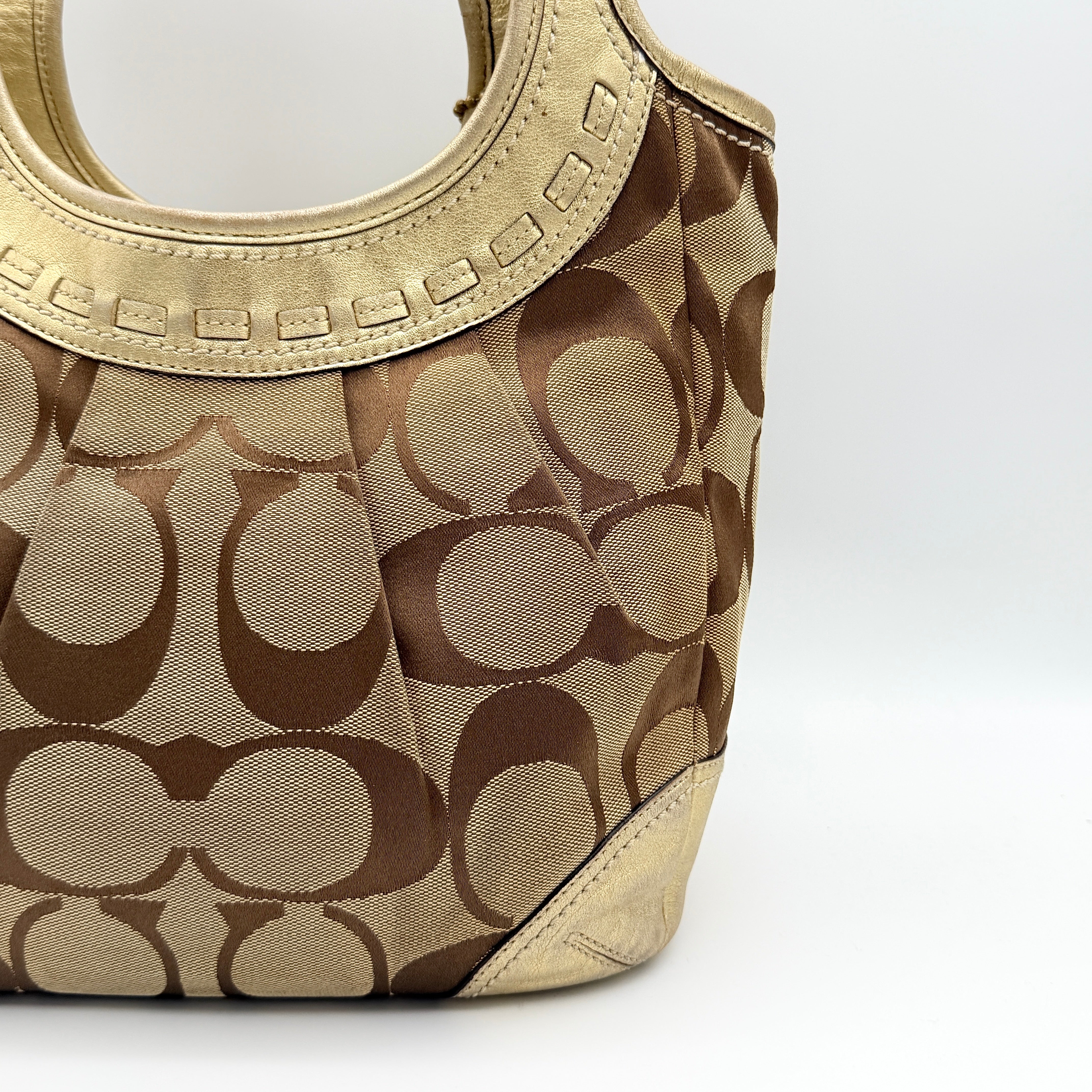 Coach Ergo Hobo Shoulder Bag in beige jacquard canvas with gold leather trim, shown standing upright against a white background.