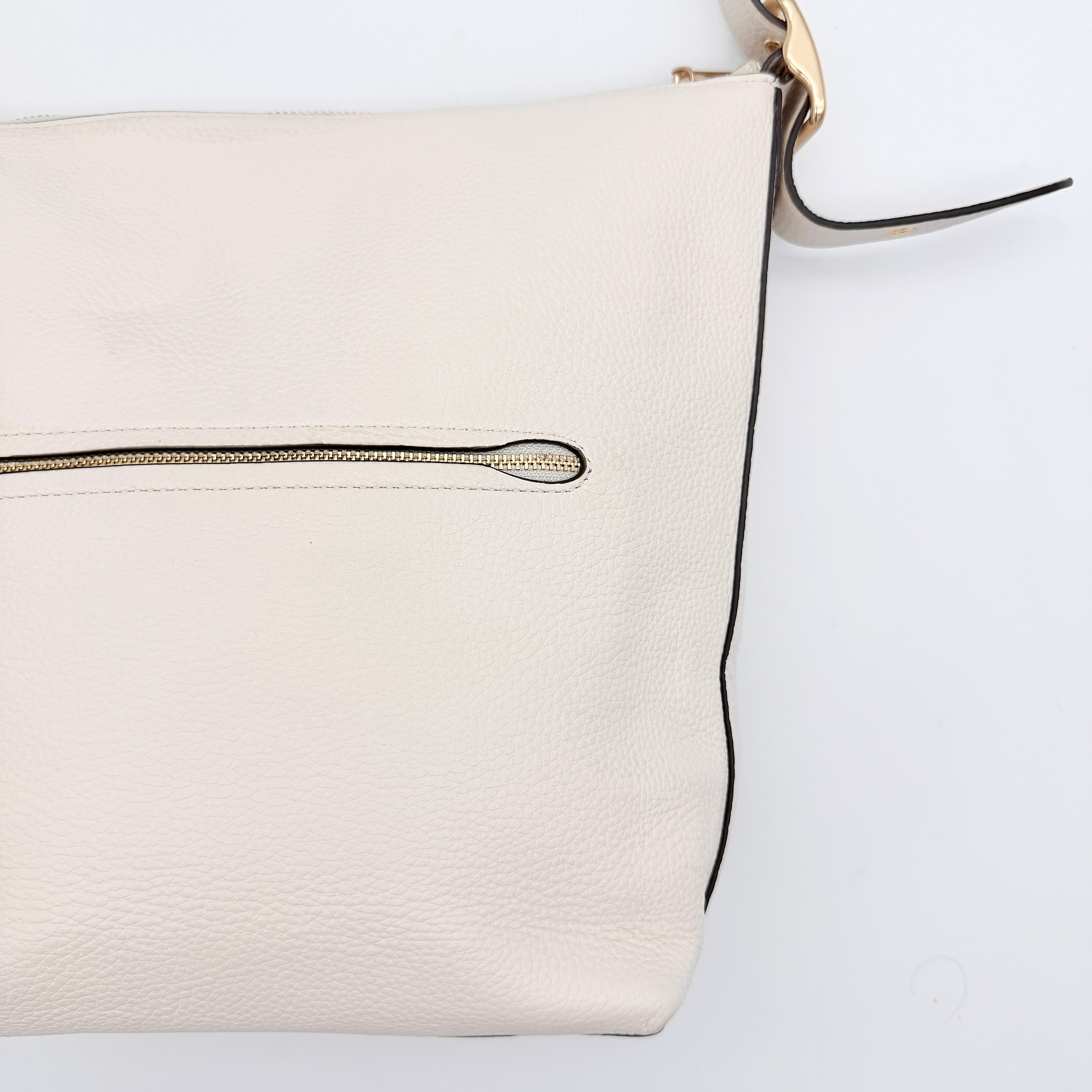 Coach Ellie File Crossbody Bag in ivory pebbled leather with gold hardware and adjustable strap, displayed on a white background.