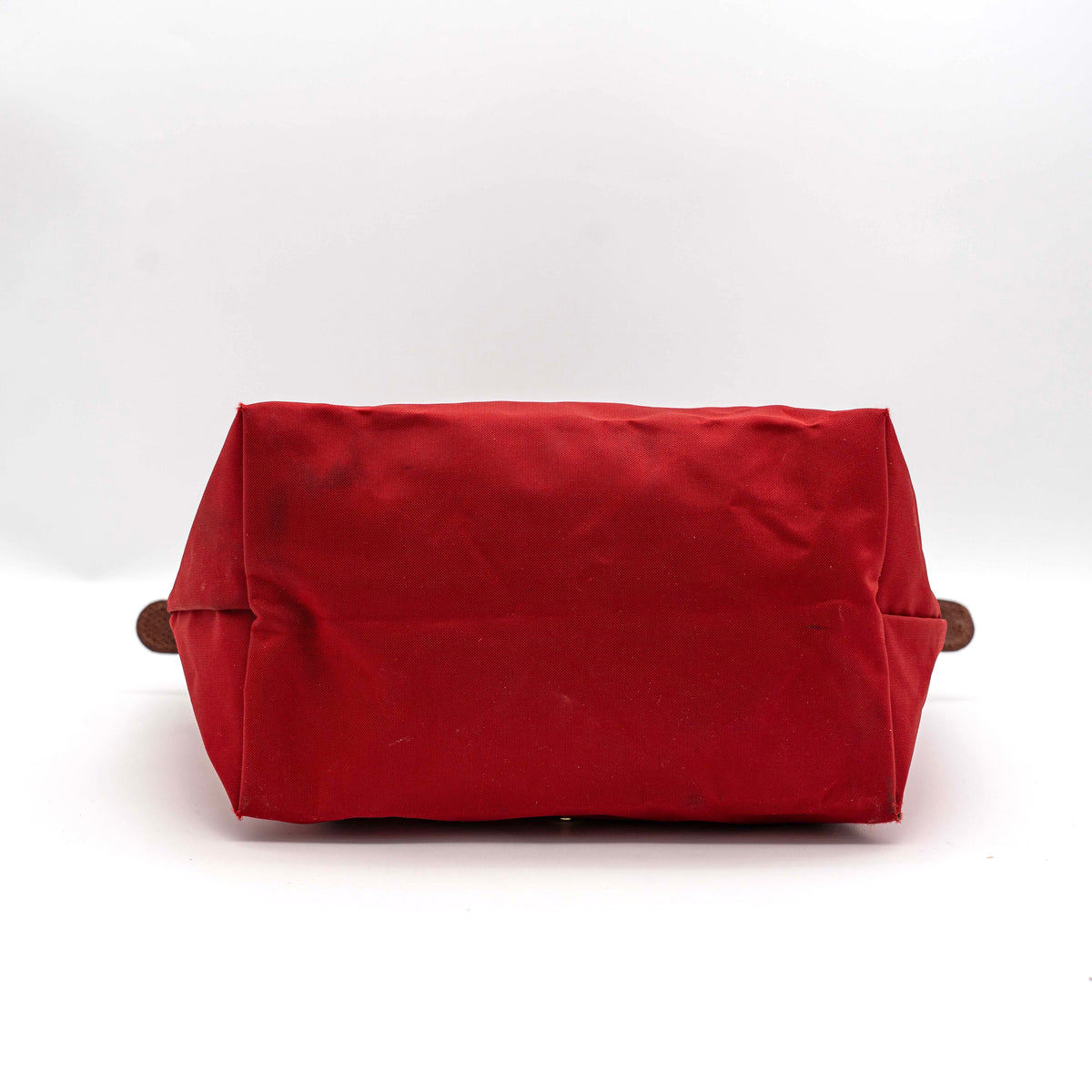Longchamp Le Pliage handbag in red nylon with brown leather handles and gold-tone accents, photographed on a white background.