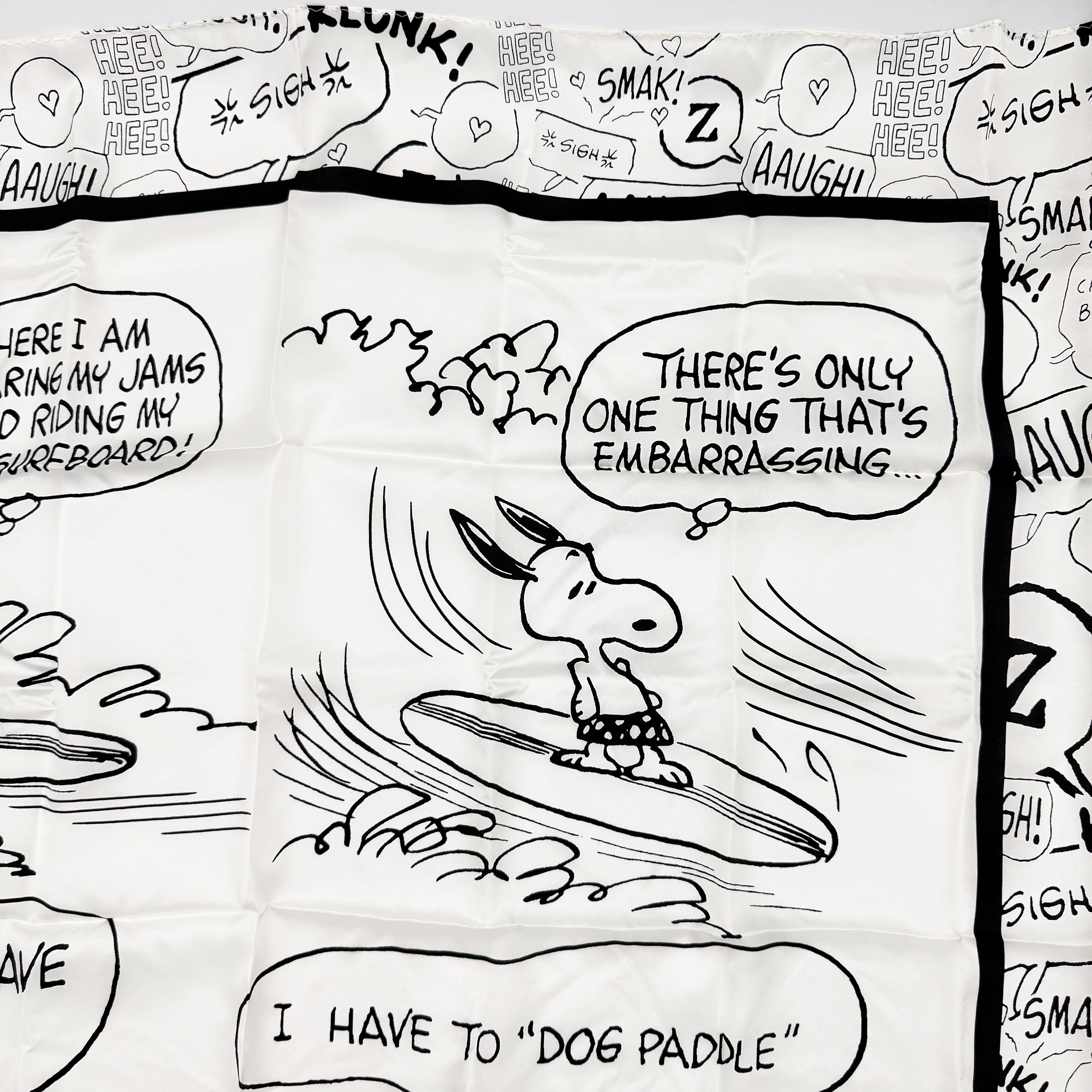Coach x Peanuts black and white silk scarf featuring a Snoopy surfing comic print, shown with Coach packaging and tags.